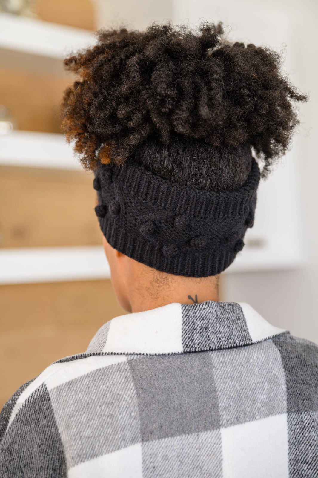 Black Pom Knit Headwrap featuring a bow front and pom pom detailing, made from soft ribbed knit material.