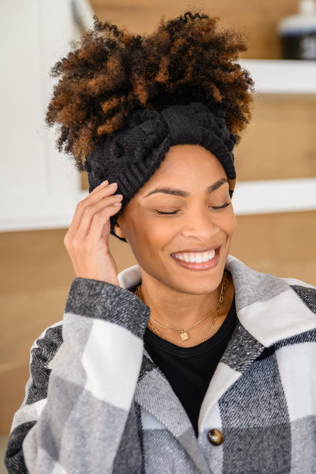 Black Pom Knit Headwrap featuring a bow front and pom pom detailing, made from soft ribbed knit material.