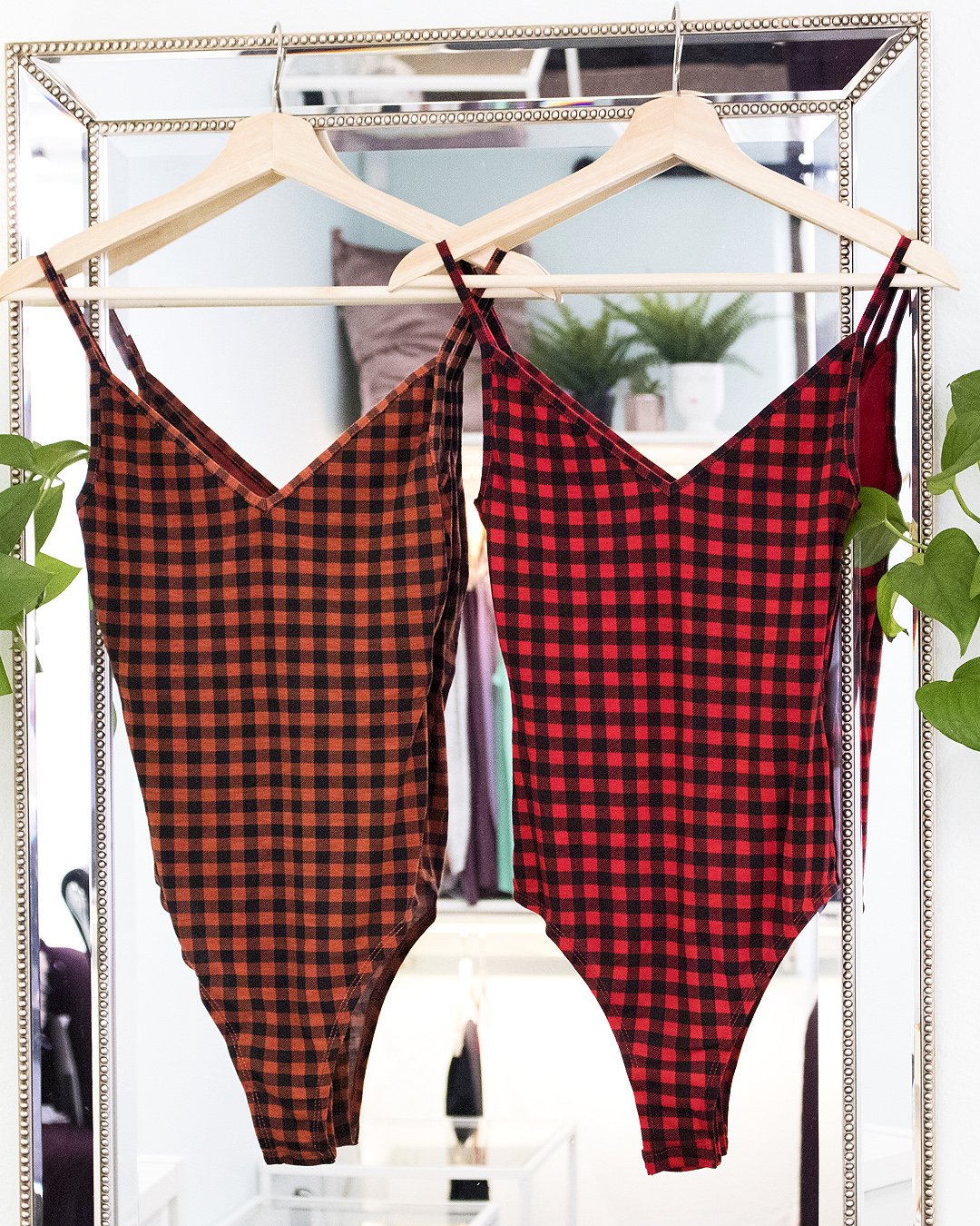 A stylish Pretty in Plaid Bodysuit in rust orange and red colors, showcasing its flattering fit and trendy plaid design.