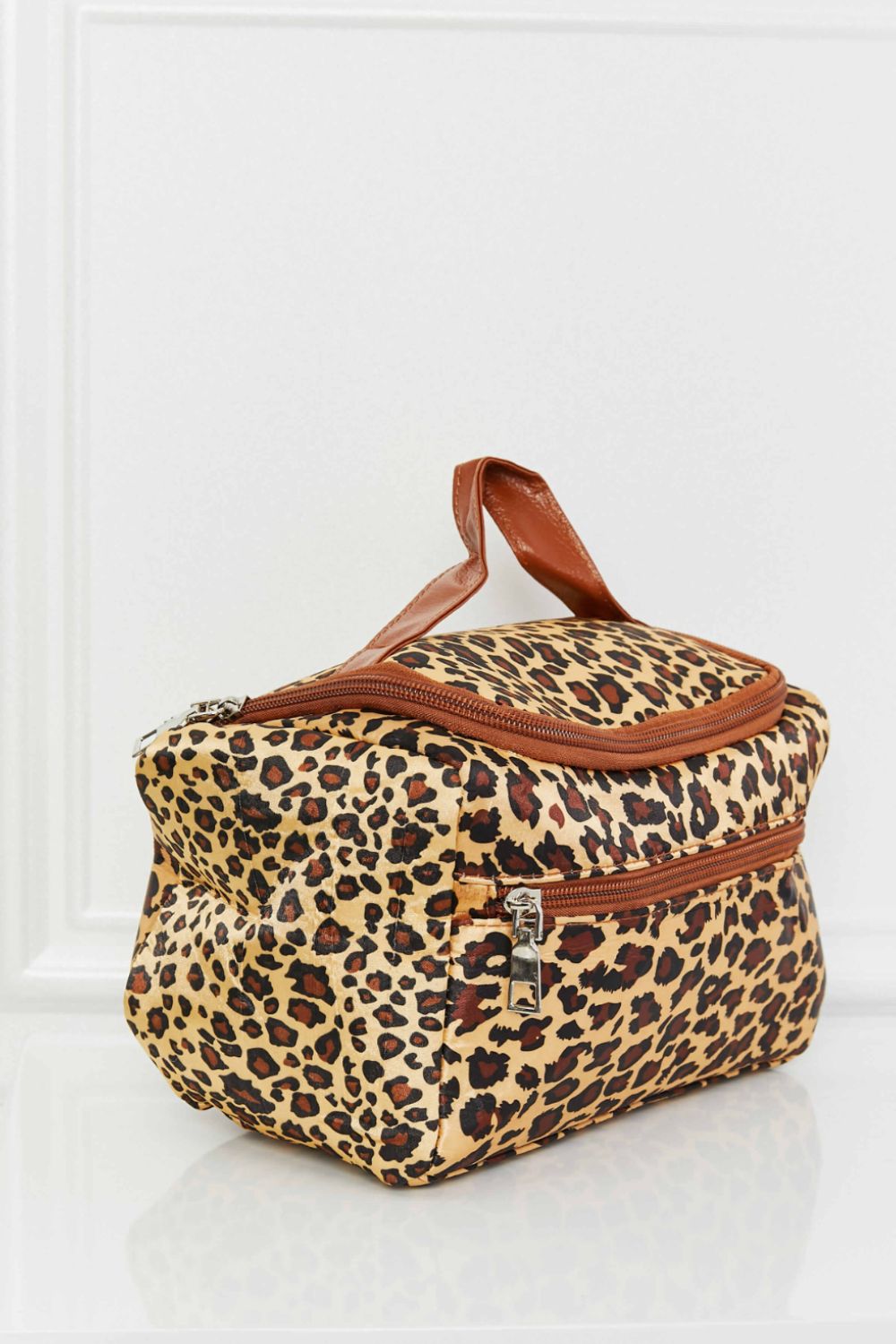 A stylish printed makeup bag featuring leopard and plaid patterns, equipped with a top handle strap for easy carrying.