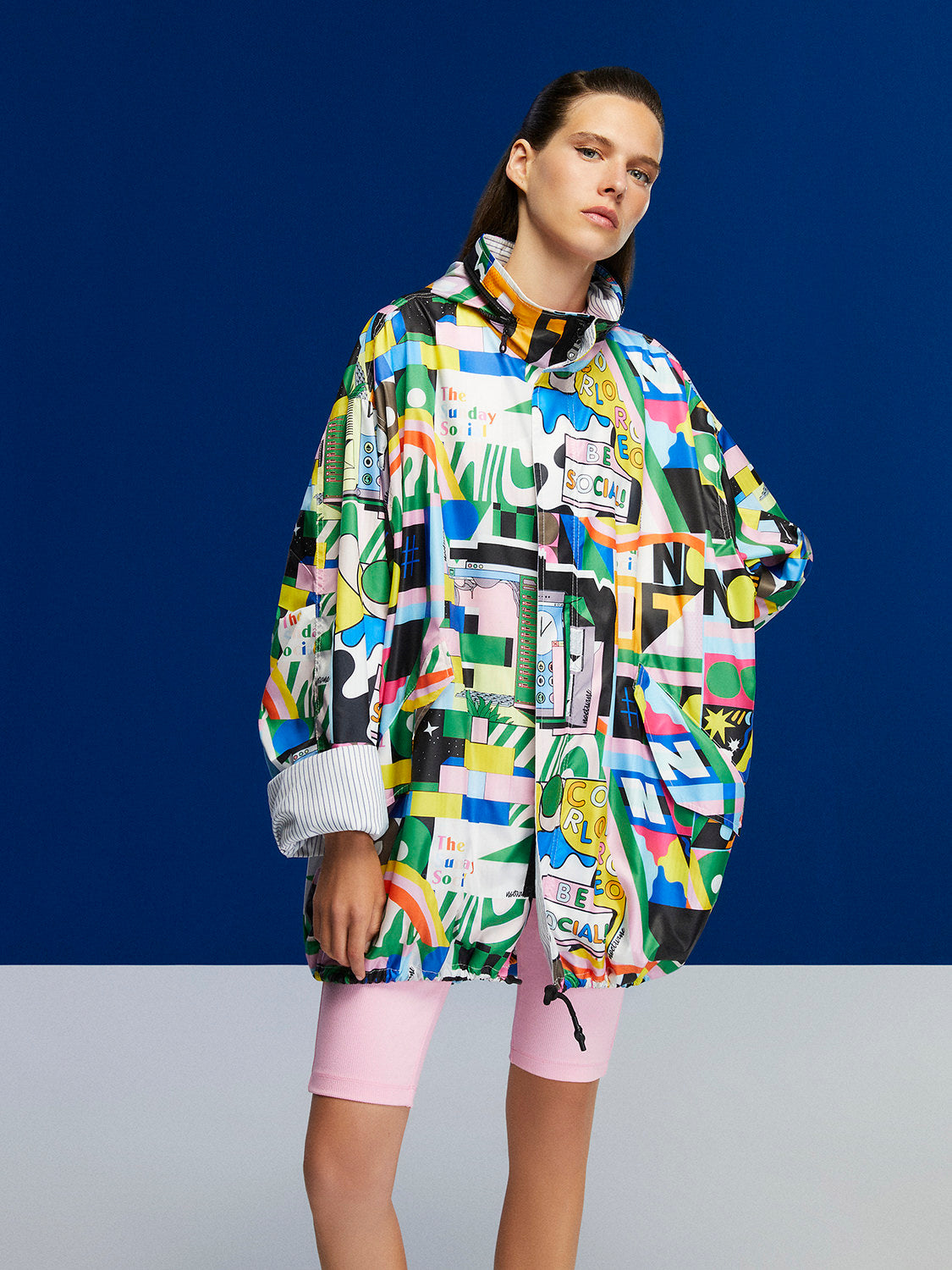 A stylish printed oversized raincoat with a high collar, hidden hood, and vibrant colors, perfect for rainy days.