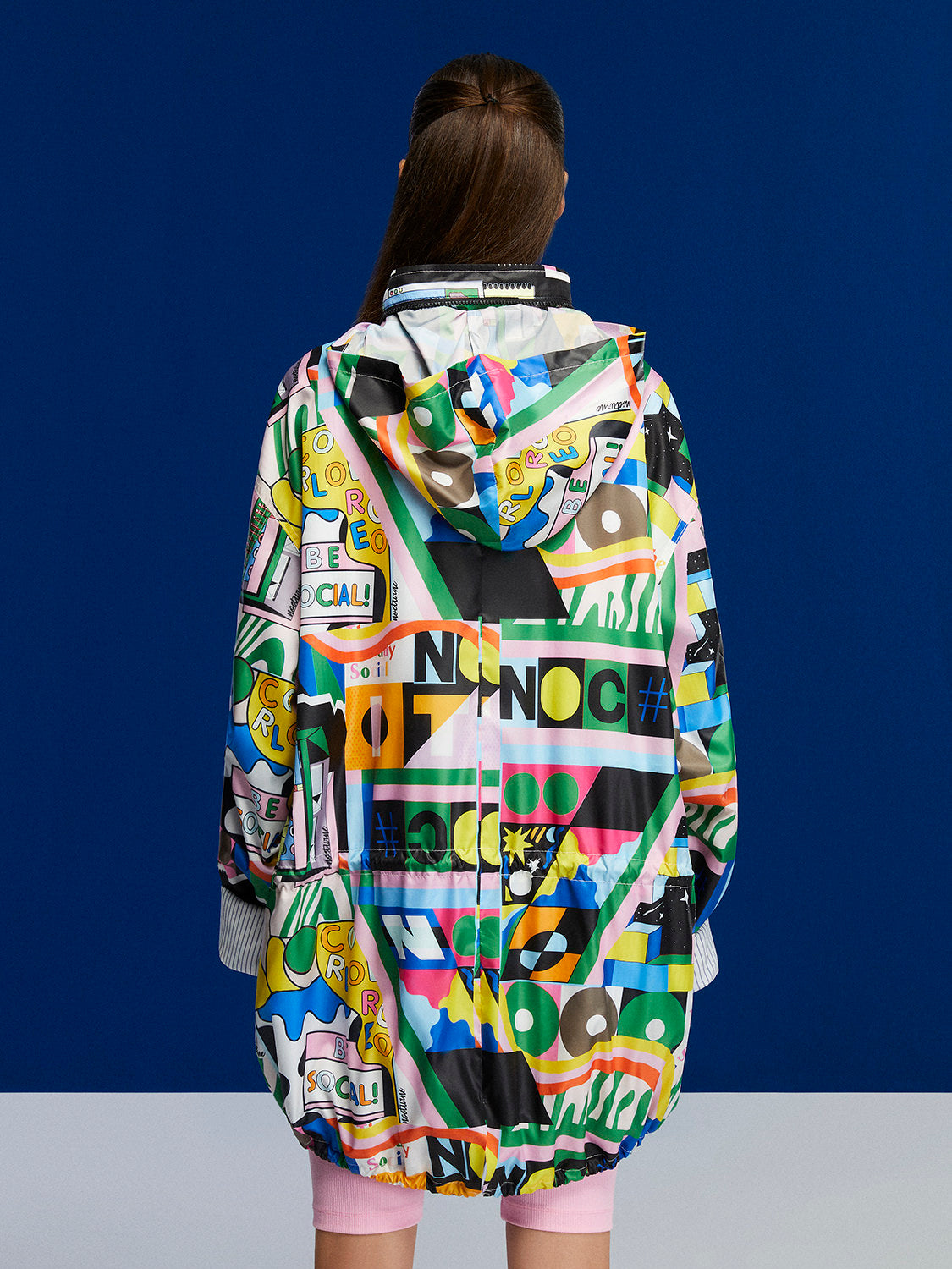 A stylish printed oversized raincoat with a high collar, hidden hood, and vibrant colors, perfect for rainy days.