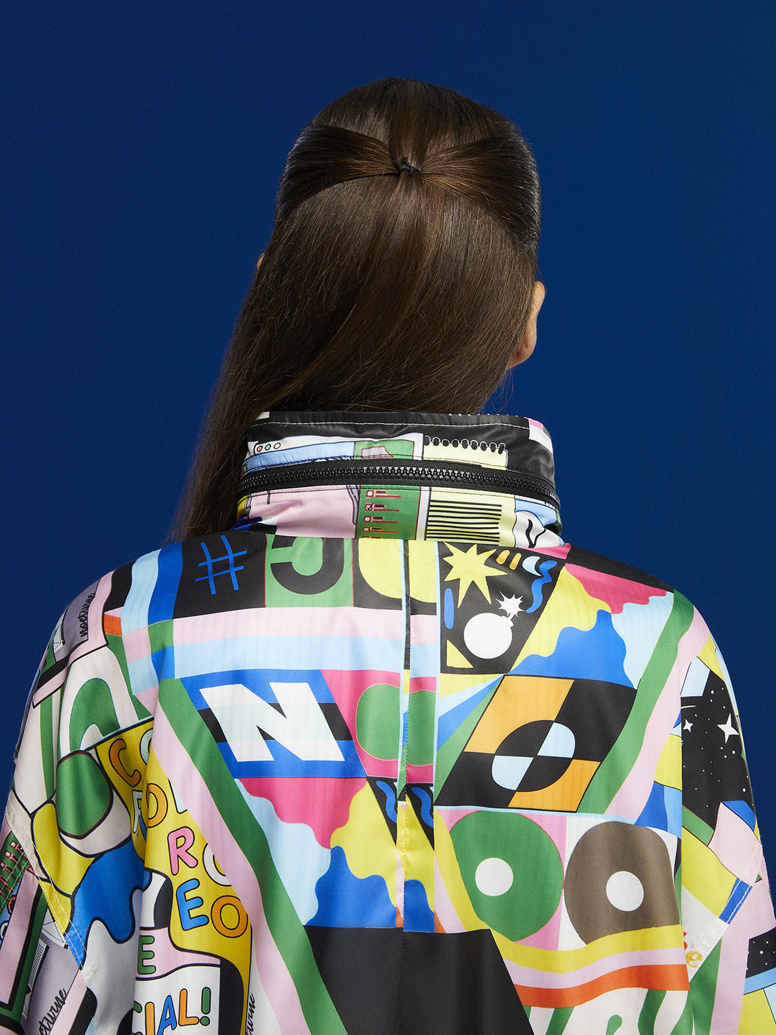 A stylish printed oversized raincoat with a high collar, hidden hood, and vibrant colors, perfect for rainy days.