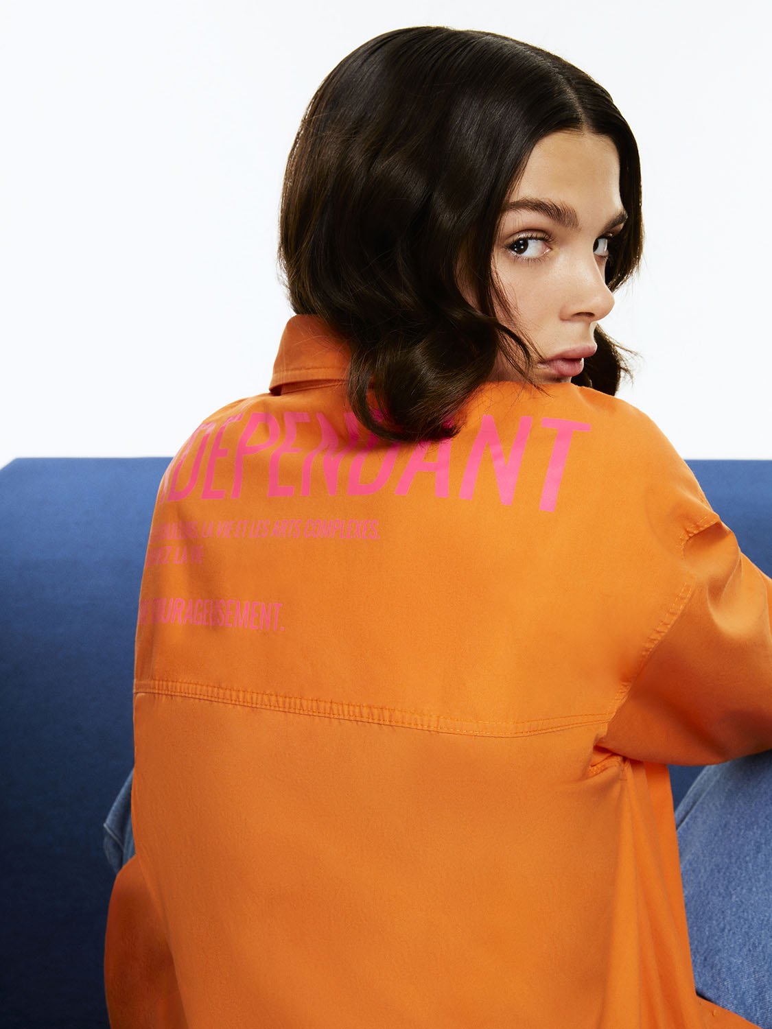 A vibrant Printed Oversized Shirt featuring orange, pink, and blue colors with long sleeves and a printed text detail on the back.