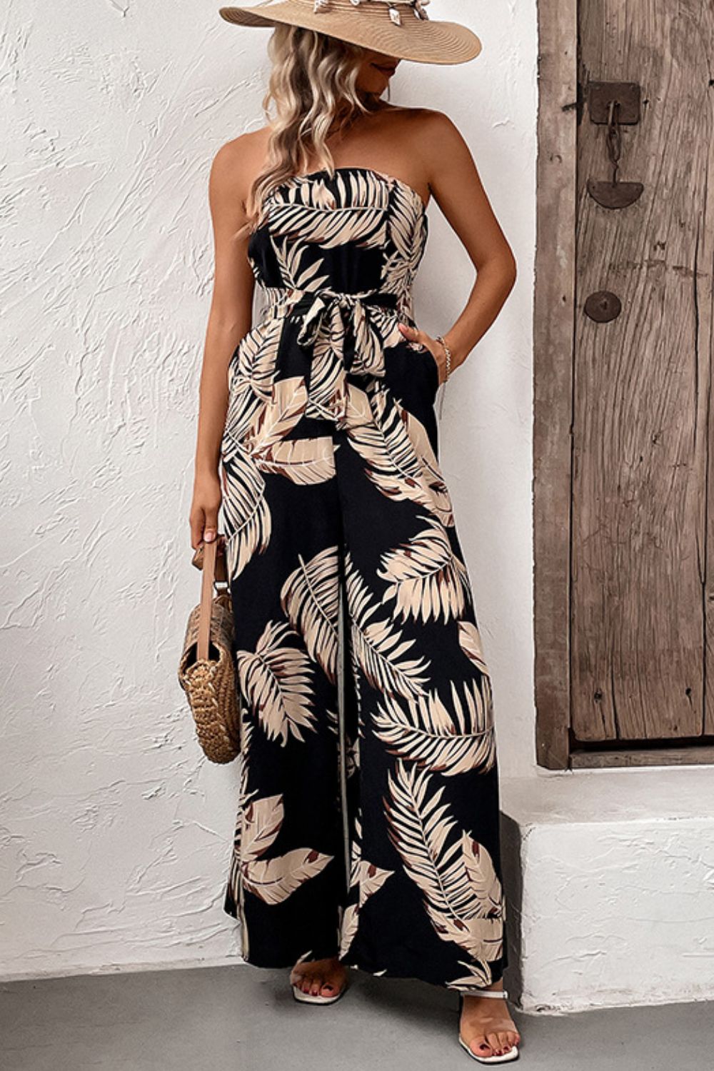 A stylish printed strapless wide leg jumpsuit with pockets, featuring a belted waist and sleeveless design, perfect for chic urban outings.