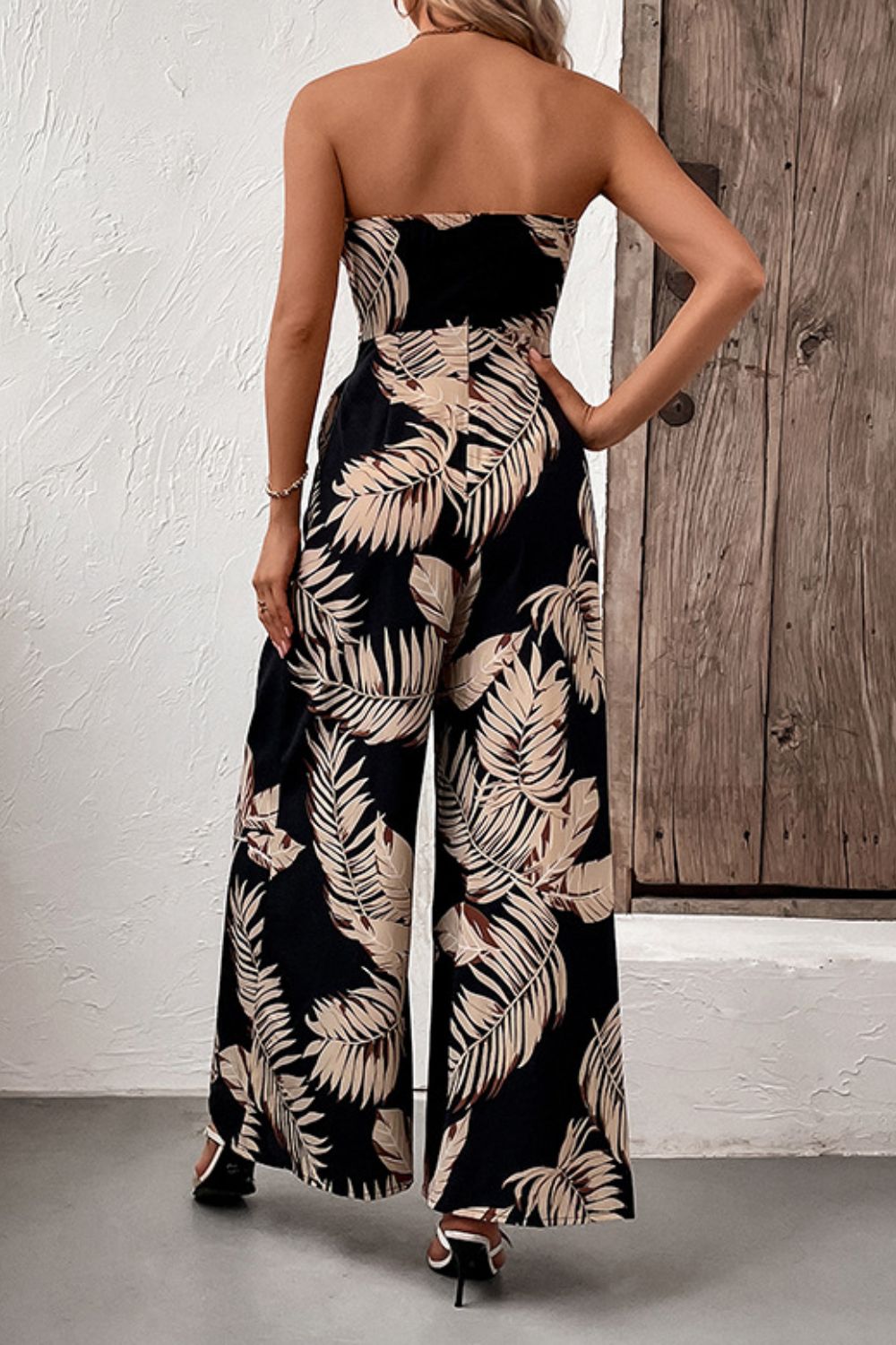 A stylish printed strapless wide leg jumpsuit with pockets, featuring a belted waist and sleeveless design, perfect for chic urban outings.