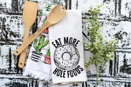 A collection of colorful Punny Tea Towels featuring humorous sayings, made from 100% cotton, displayed in a bright kitchen setting.