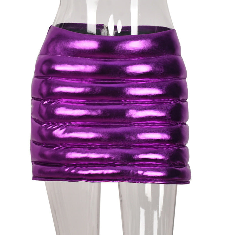 Purple women's puffer skirt with metallic shiny finish, featuring a quilted design and zipper closure, perfect for stylish warmth.