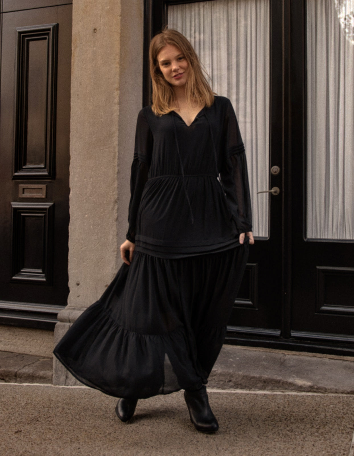 Raissa Midi Dress in solid black featuring a tiered skirt, semi-sheer sleeves, and a keyhole neckline detail.