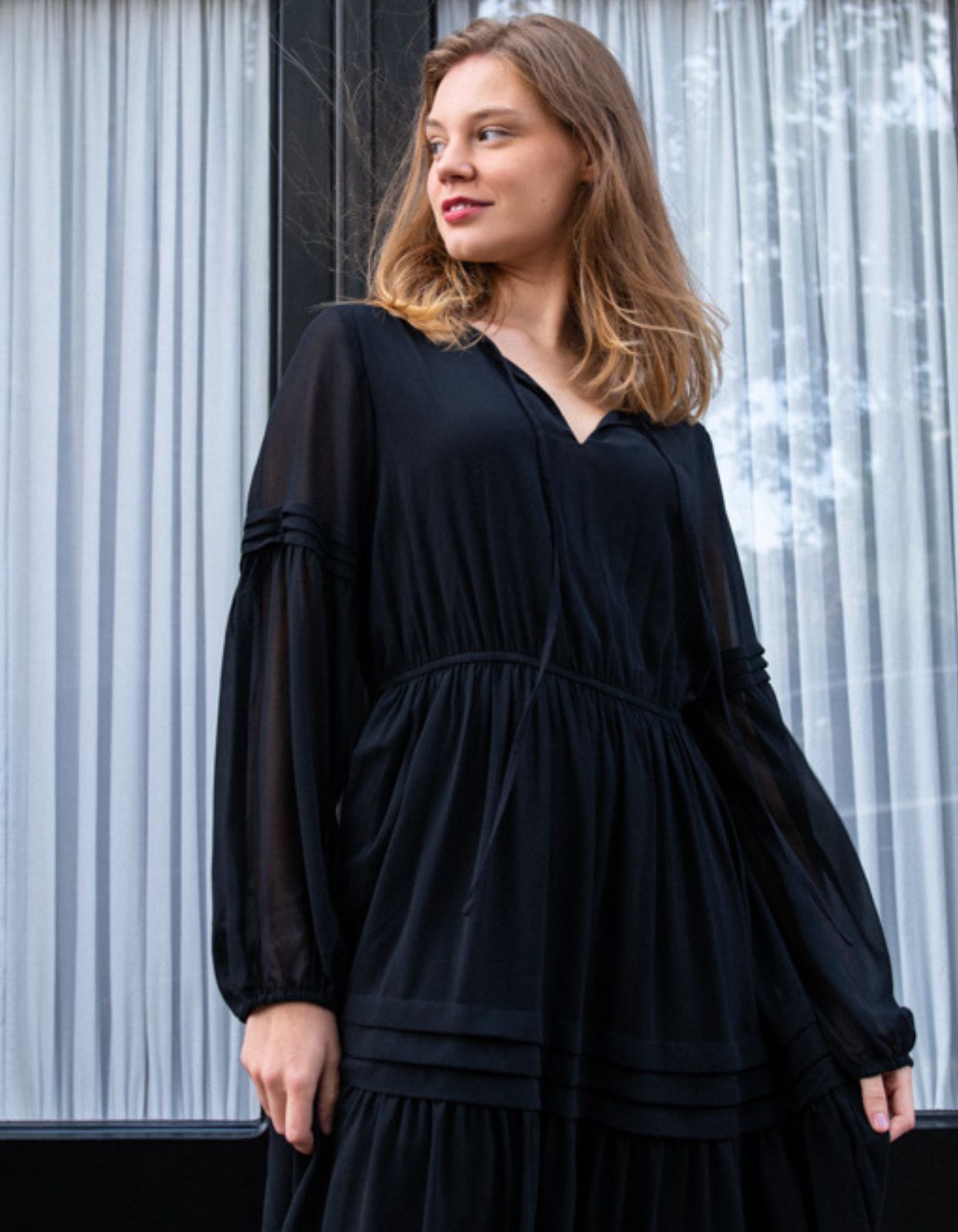 Raissa Midi Dress in solid black featuring a tiered skirt, semi-sheer sleeves, and a keyhole neckline detail.