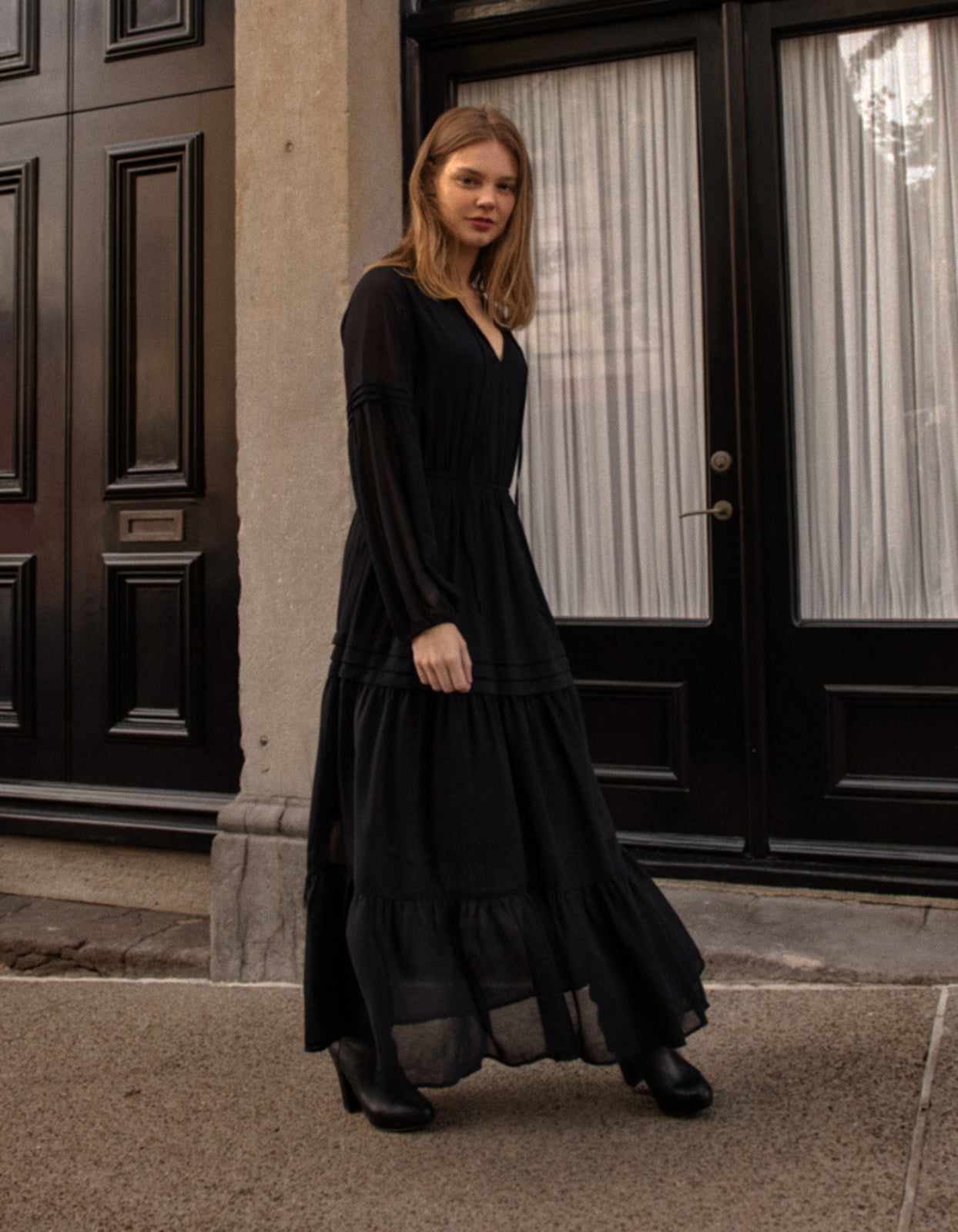 Raissa Midi Dress in solid black featuring a tiered skirt, semi-sheer sleeves, and a keyhole neckline detail.