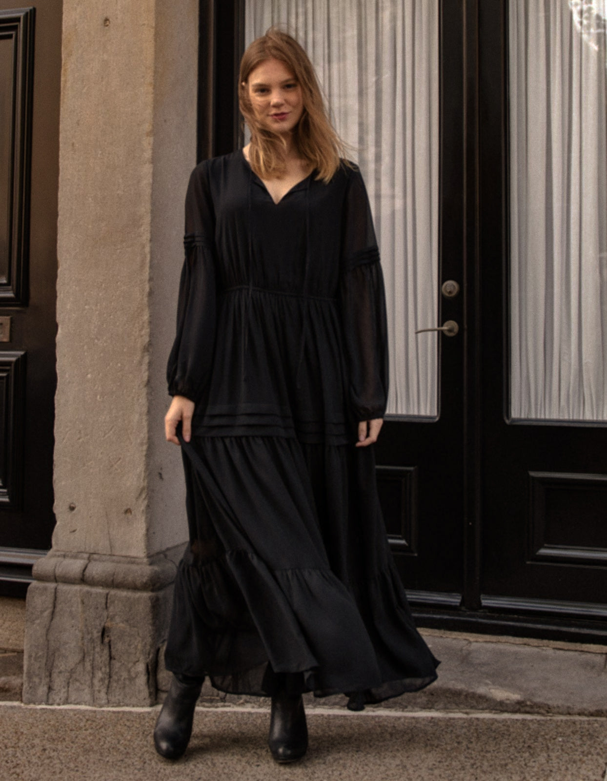 Raissa Midi Dress in solid black featuring a tiered skirt, semi-sheer sleeves, and a keyhole neckline detail.