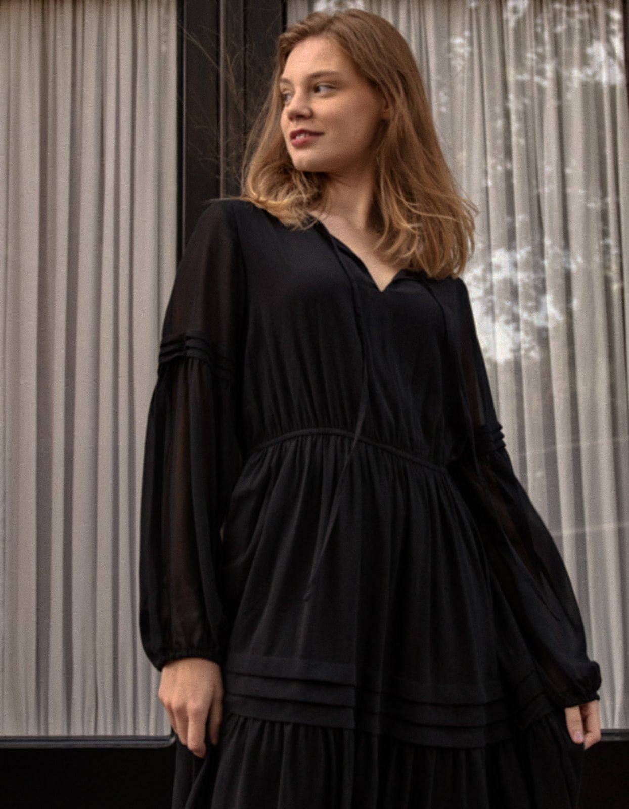 Raissa Midi Dress in solid black featuring a tiered skirt, semi-sheer sleeves, and a keyhole neckline detail.