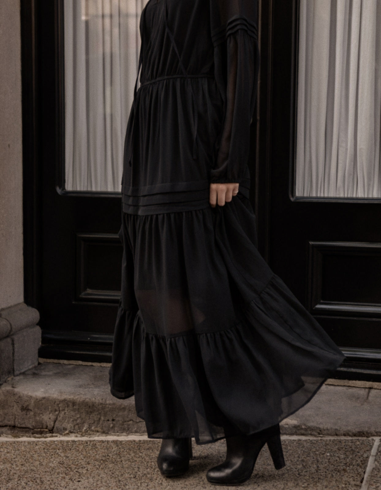 Raissa Midi Dress in solid black featuring a tiered skirt, semi-sheer sleeves, and a keyhole neckline detail.