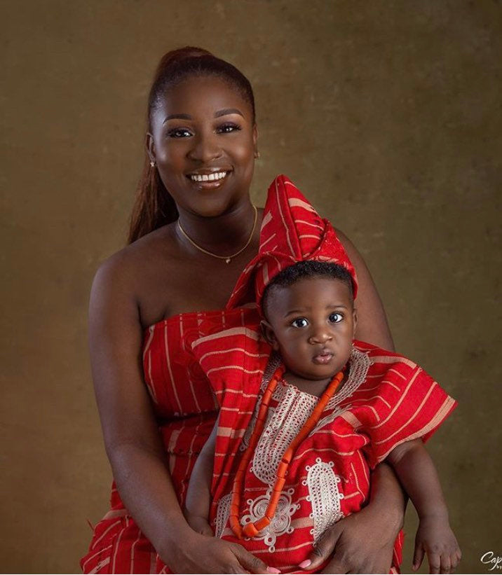 A young boy dressed in a vibrant red asooke outfit, showcasing traditional African attire with intricate patterns.