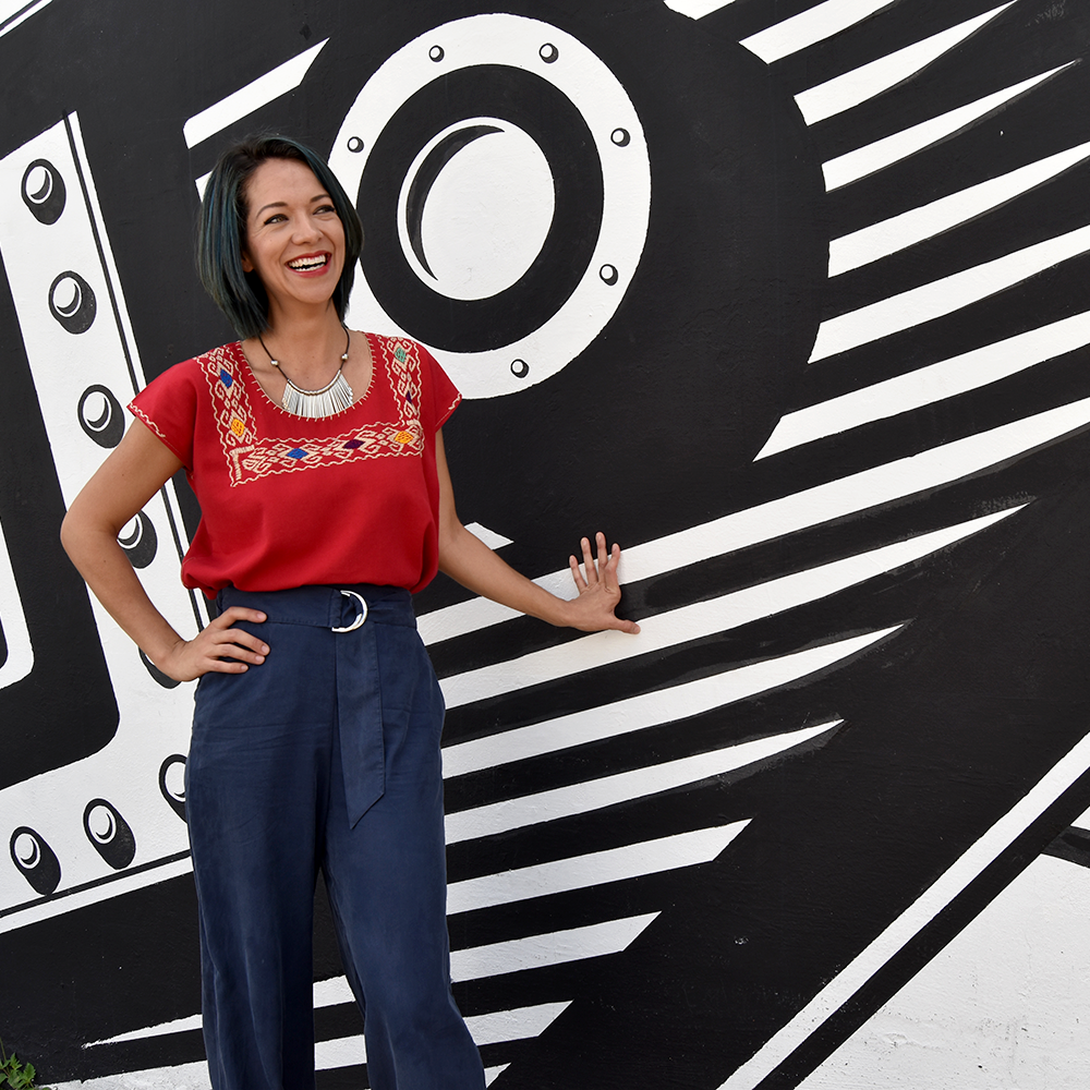 A vibrant red blouse huipil featuring colorful hand-stitched designs, showcasing traditional Mexican craftsmanship.