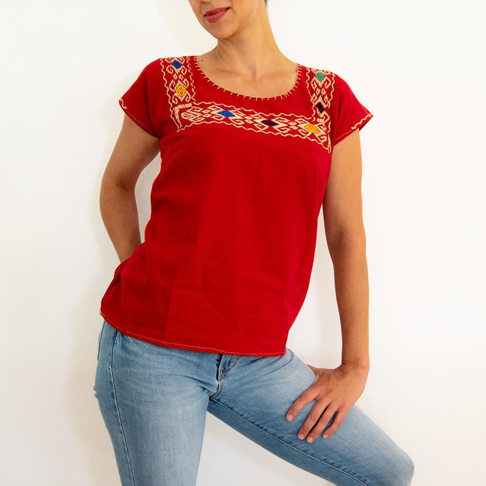 A vibrant red blouse huipil featuring colorful hand-stitched designs, showcasing traditional Mexican craftsmanship.