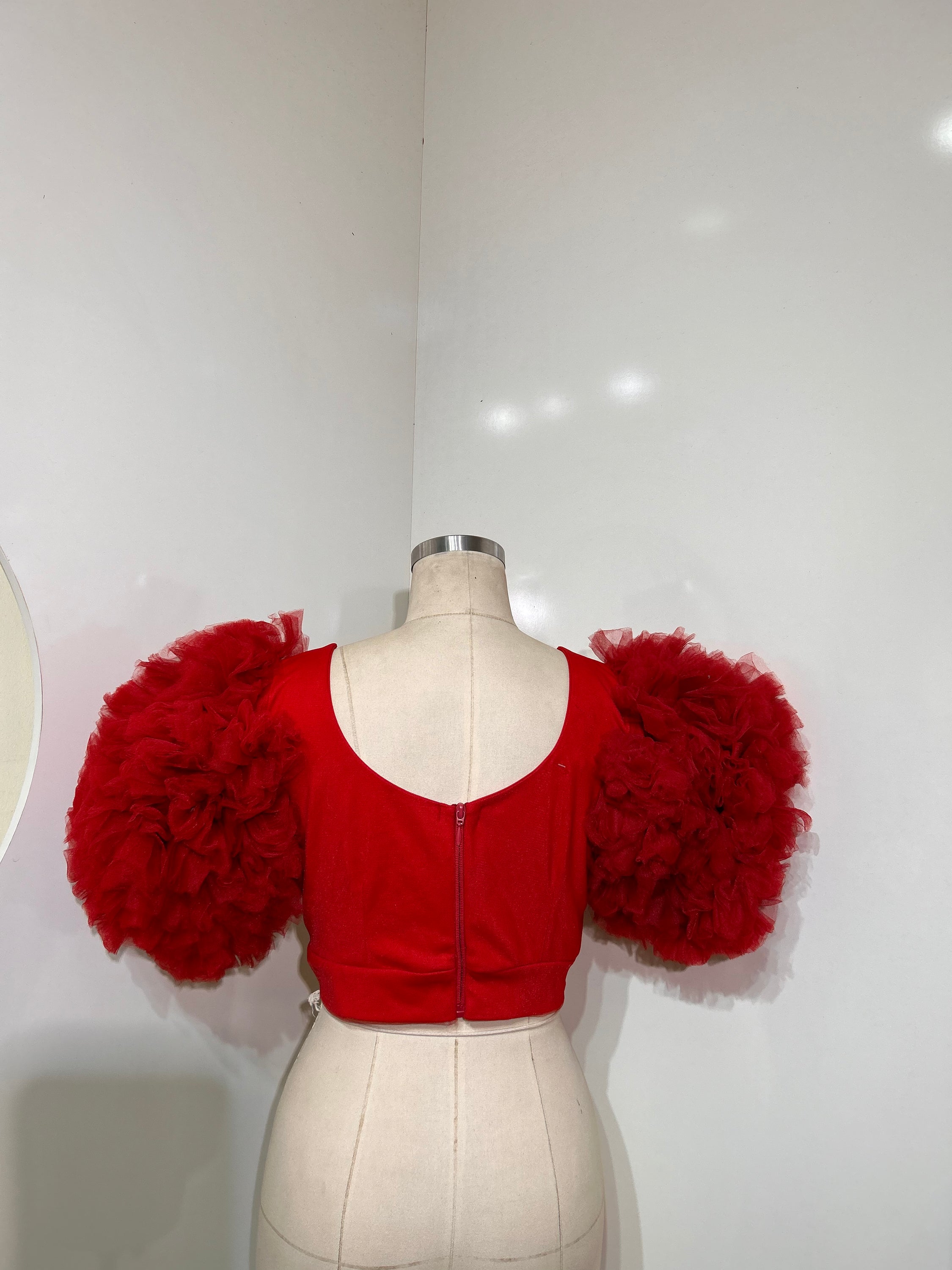 A vibrant red tulle top featuring a plunging neckline and cropped design, perfect for stylish occasions.