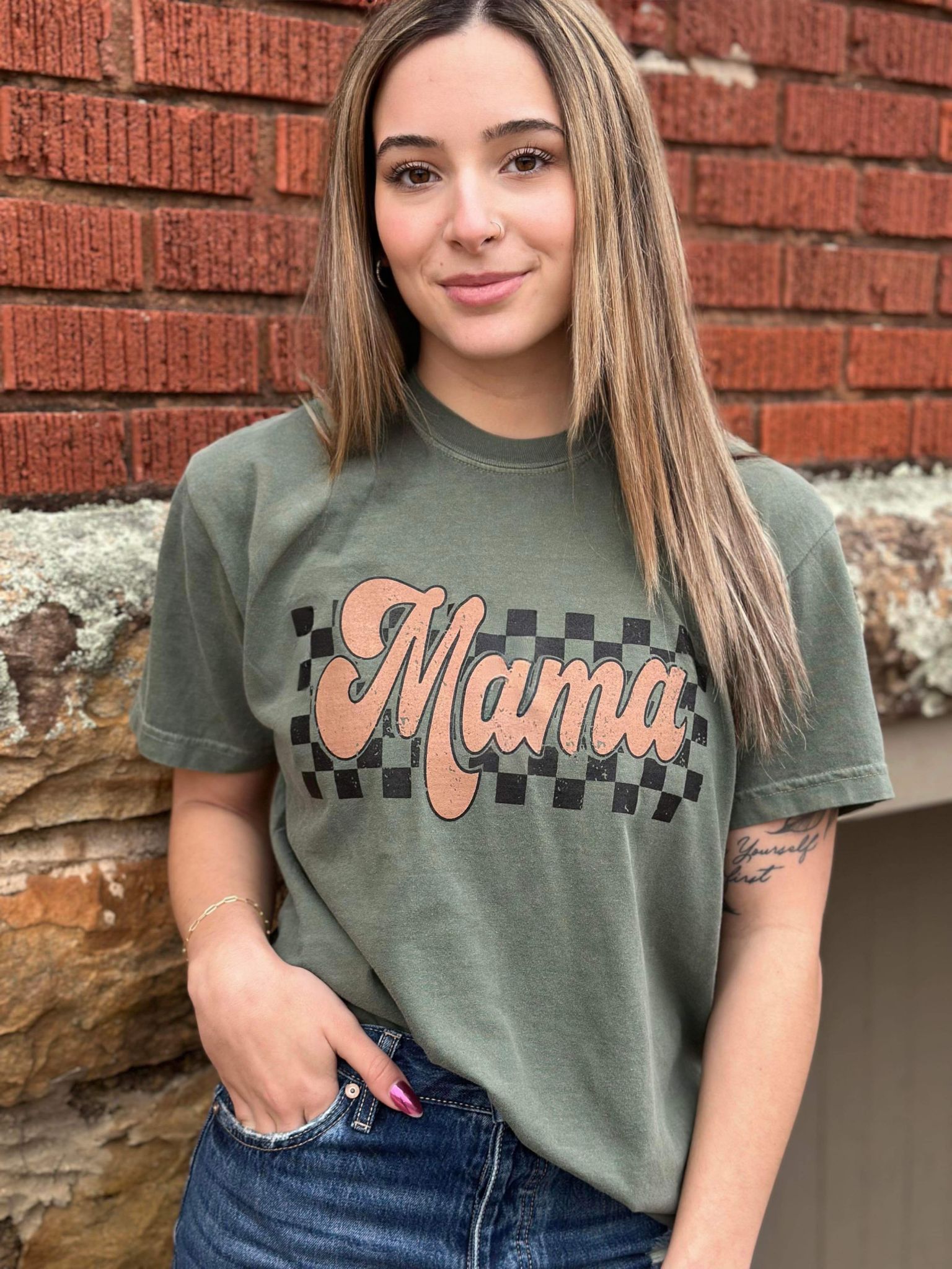 A stylish Retro Checkered Mama Tee in moss color, featuring a trendy checkered design, made from 100% cotton for comfort.