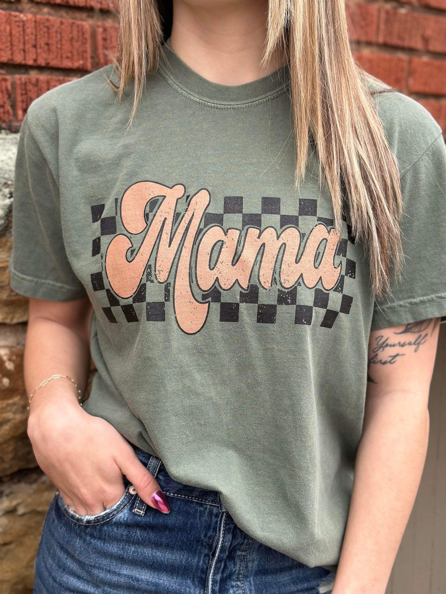 A stylish Retro Checkered Mama Tee in moss color, featuring a trendy checkered design, made from 100% cotton for comfort.