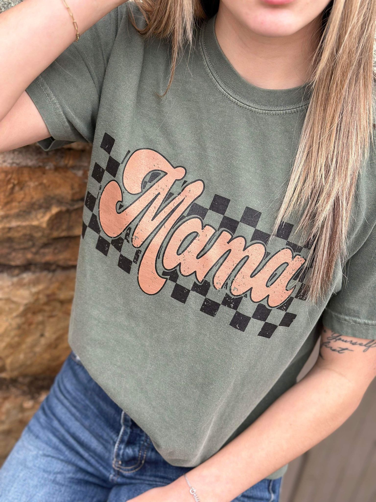 A stylish Retro Checkered Mama Tee in moss color, featuring a trendy checkered design, made from 100% cotton for comfort.