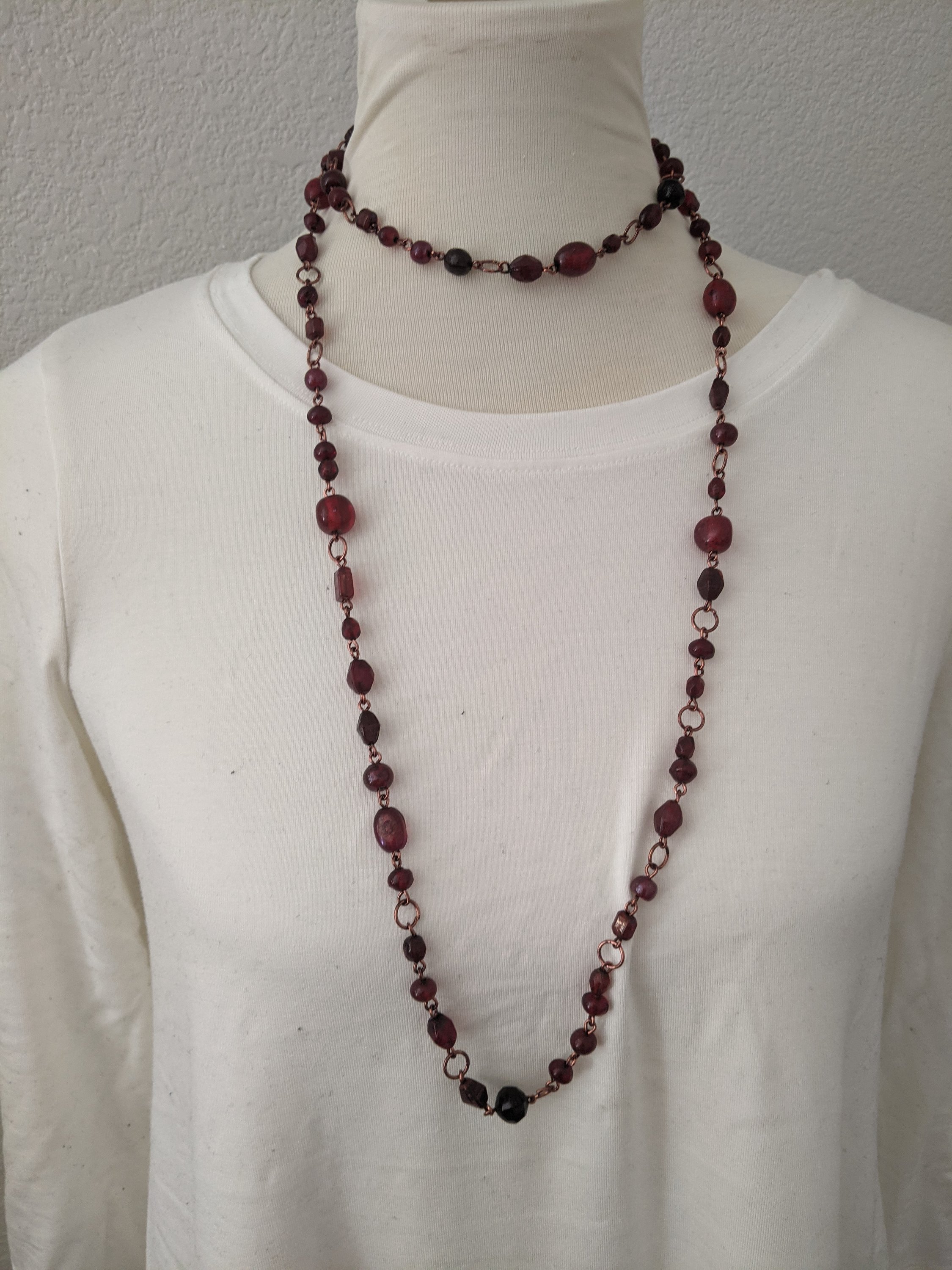 A beautiful ruby red stone long necklace elegantly displayed, showcasing its vibrant color and intricate design.