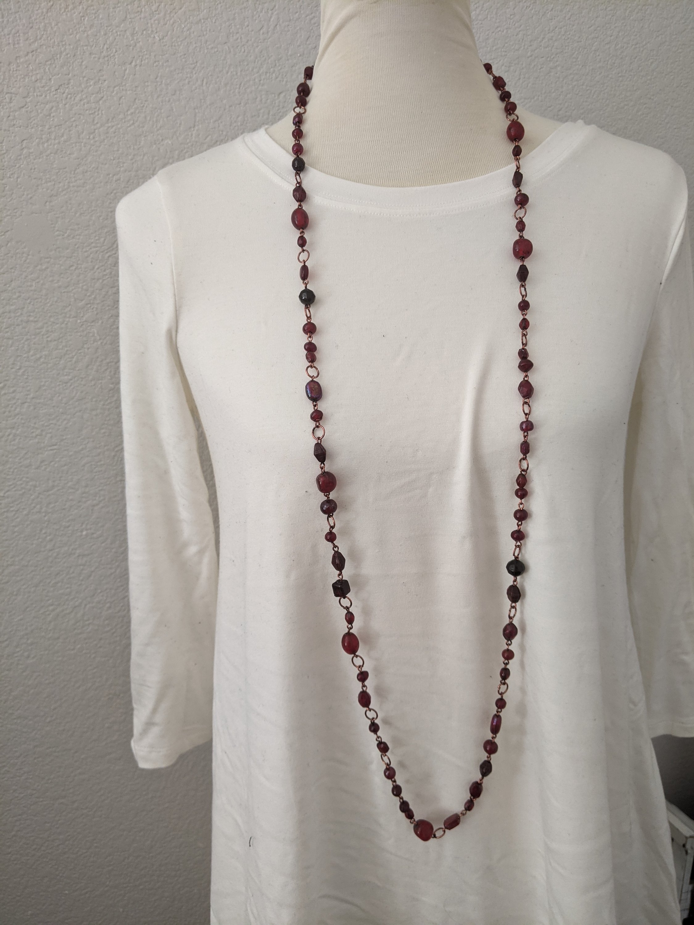 A beautiful ruby red stone long necklace elegantly displayed, showcasing its vibrant color and intricate design.