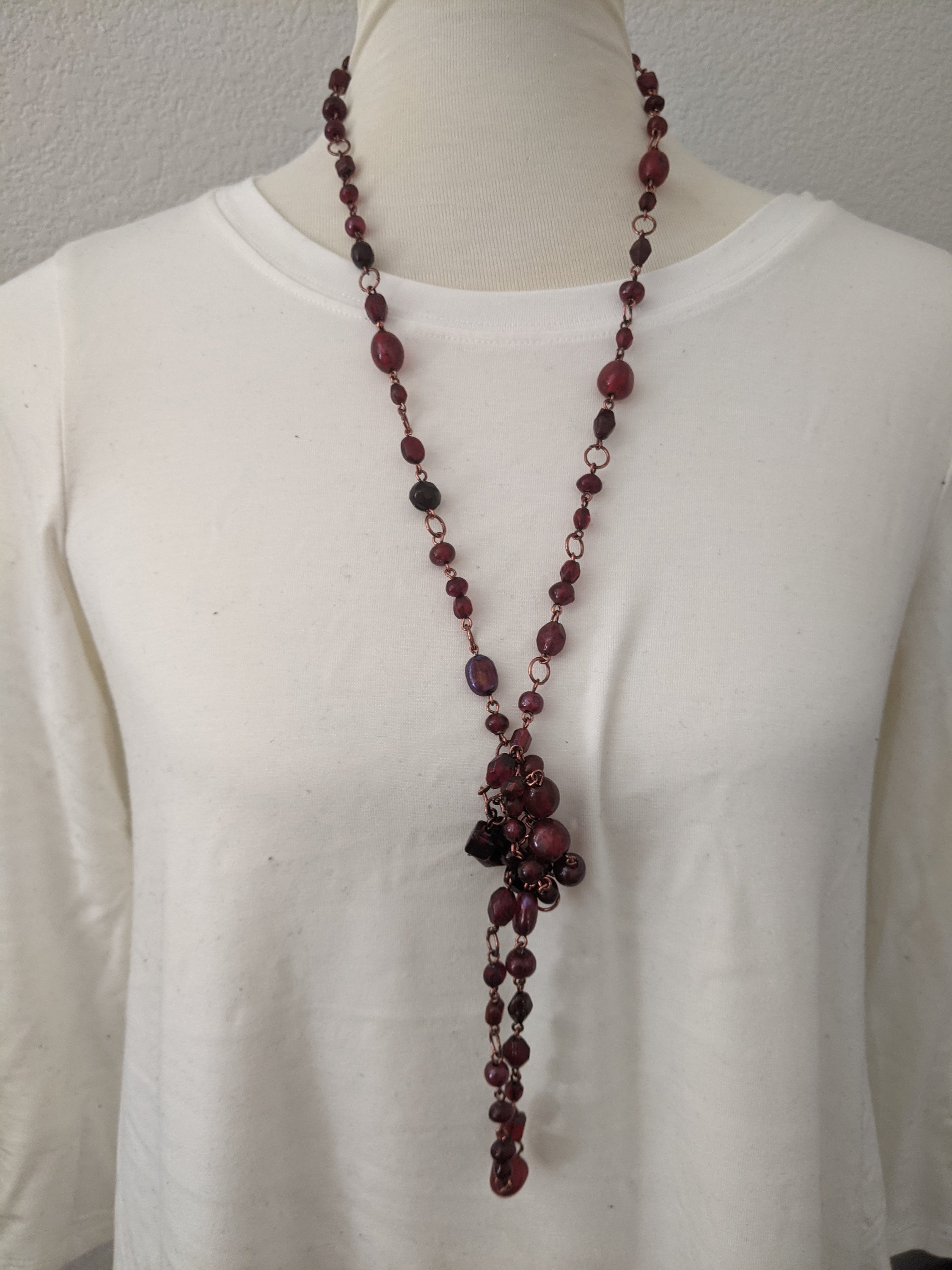 A beautiful ruby red stone long necklace elegantly displayed, showcasing its vibrant color and intricate design.