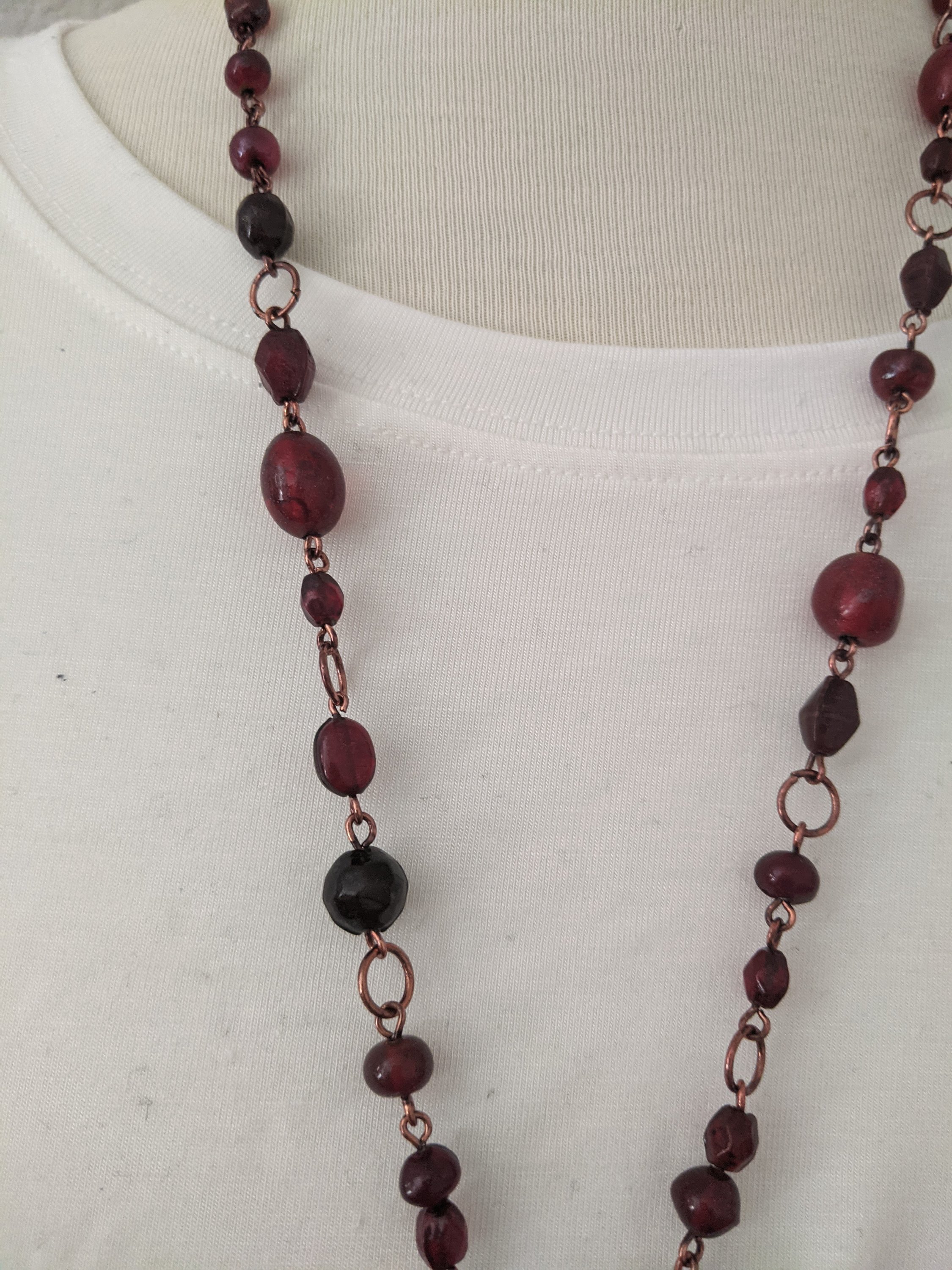 A beautiful ruby red stone long necklace elegantly displayed, showcasing its vibrant color and intricate design.