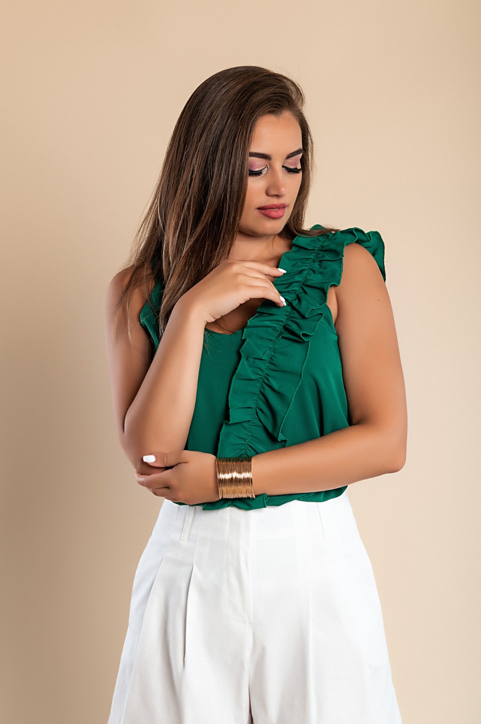 Elegant green ruffled top with spaghetti straps and deep neckline, showcasing decorative ruffles and loose fit.