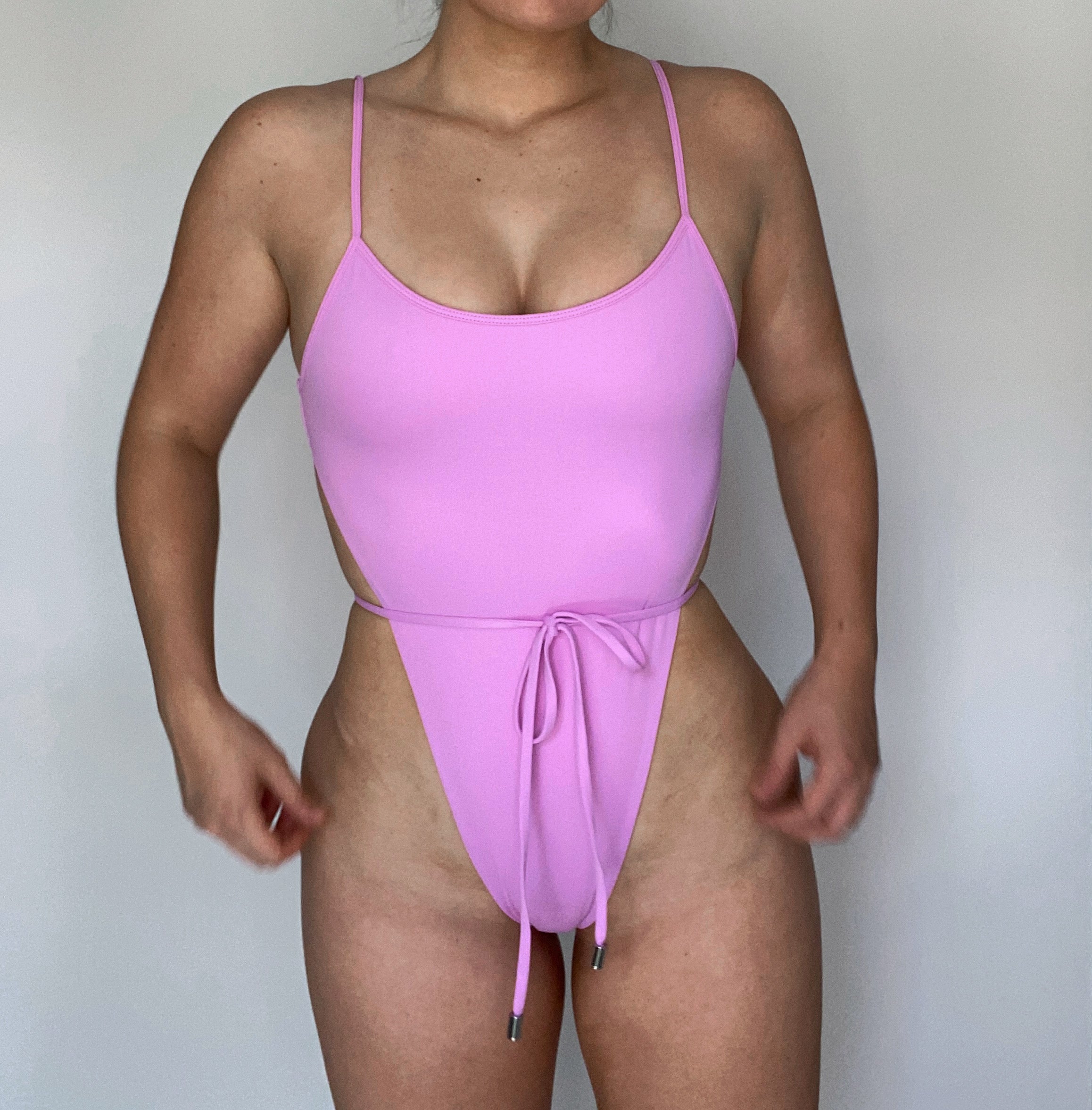 The Samira One Piece in Lilac, a sexy swimsuit with a front tie bow detail, designed to accentuate curves and made from recycled materials.