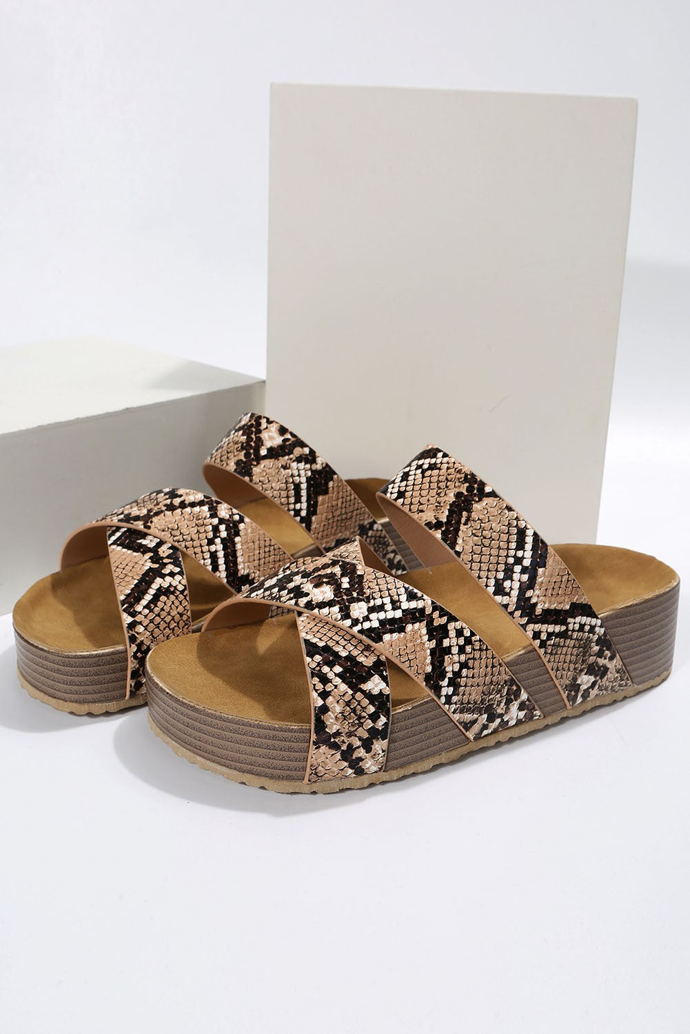 Stylish leopard print sandals featuring crossed straps and a raised sole, perfect for summer wear.