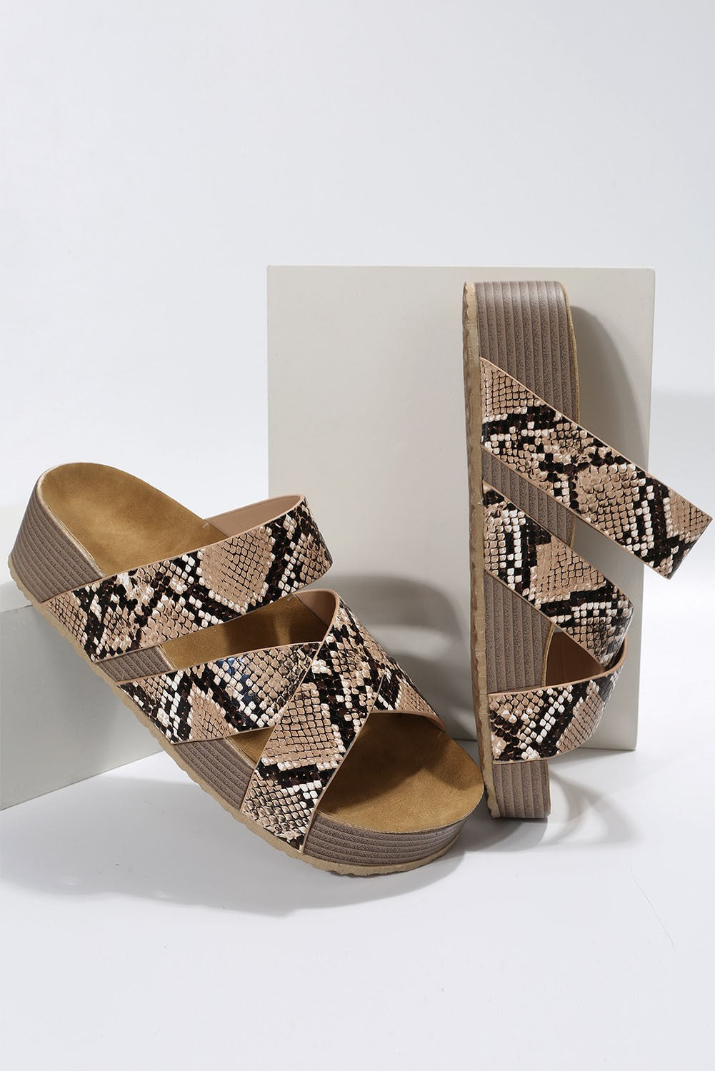 Stylish leopard print sandals featuring crossed straps and a raised sole, perfect for summer wear.