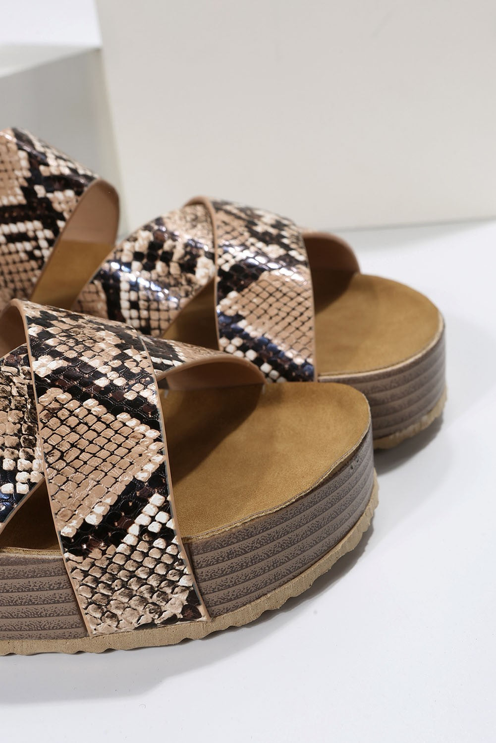 Stylish leopard print sandals featuring crossed straps and a raised sole, perfect for summer wear.