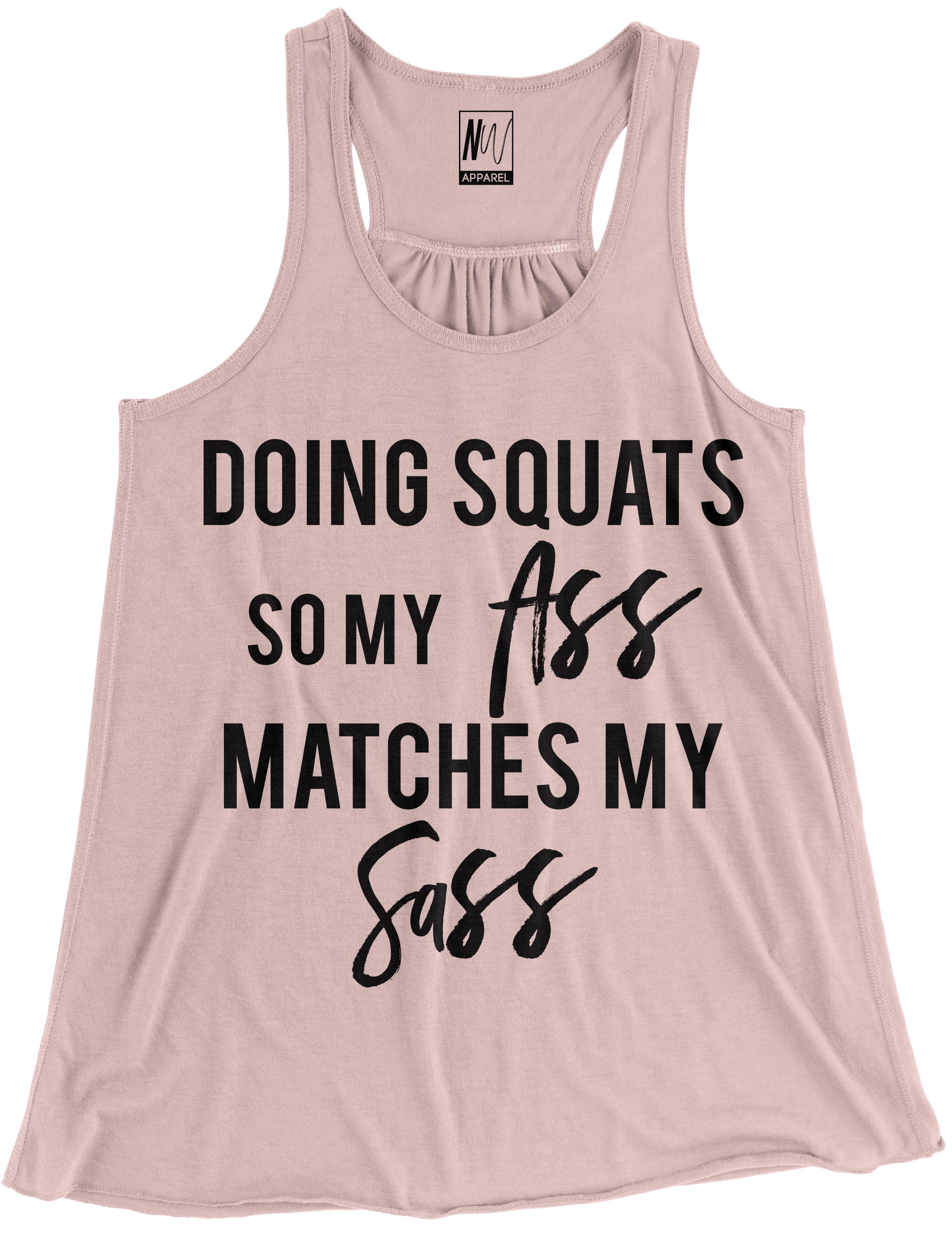 Blush flowy racerback tank top with black print saying 'DOING SQUATS SO MY ASS MATCHES MY SASS'.