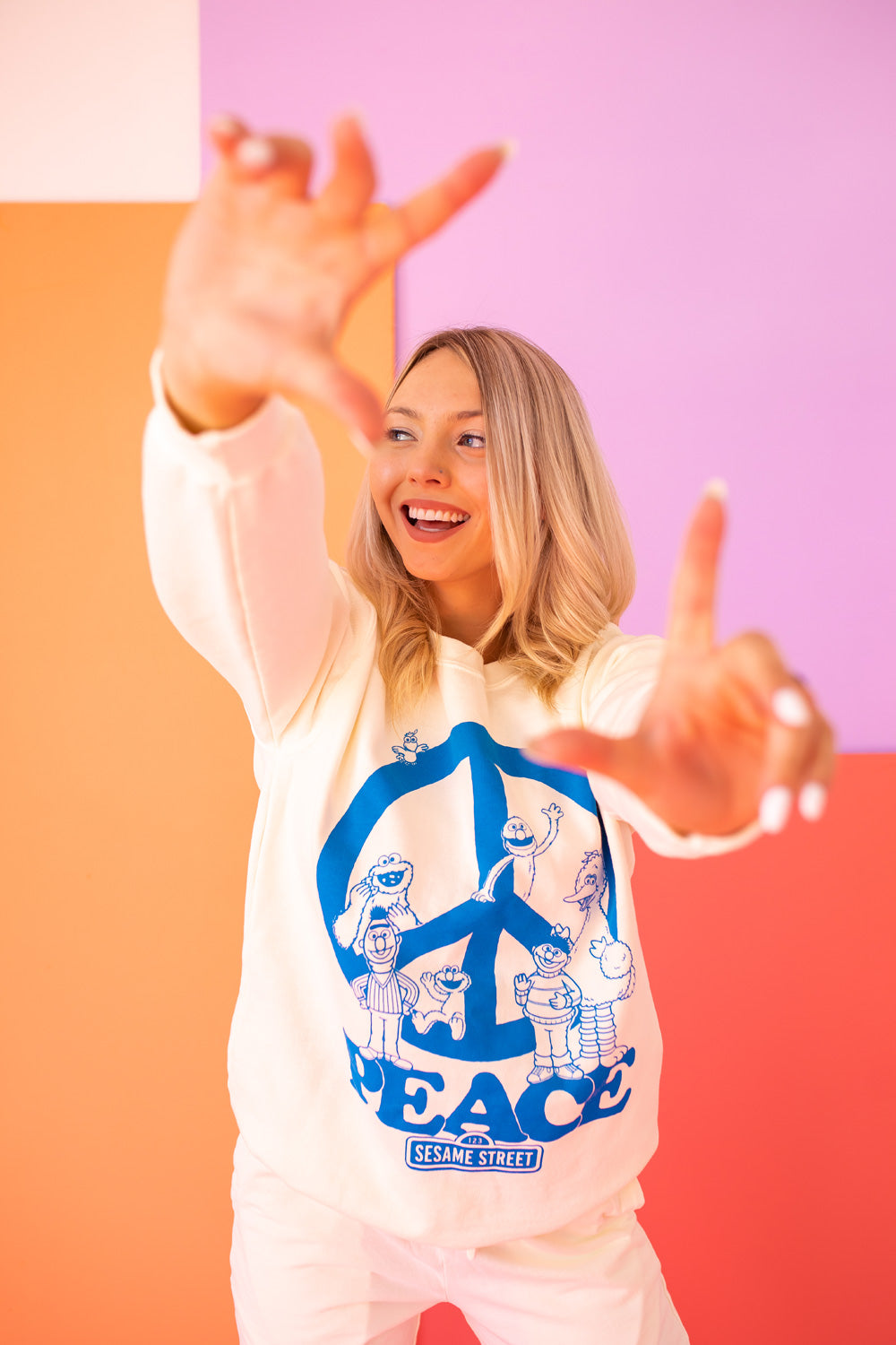 Ivory Sesame Street Peace Sweatshirt featuring bold graphics, made from 100% upcycled cotton, available in sizes S-XL.