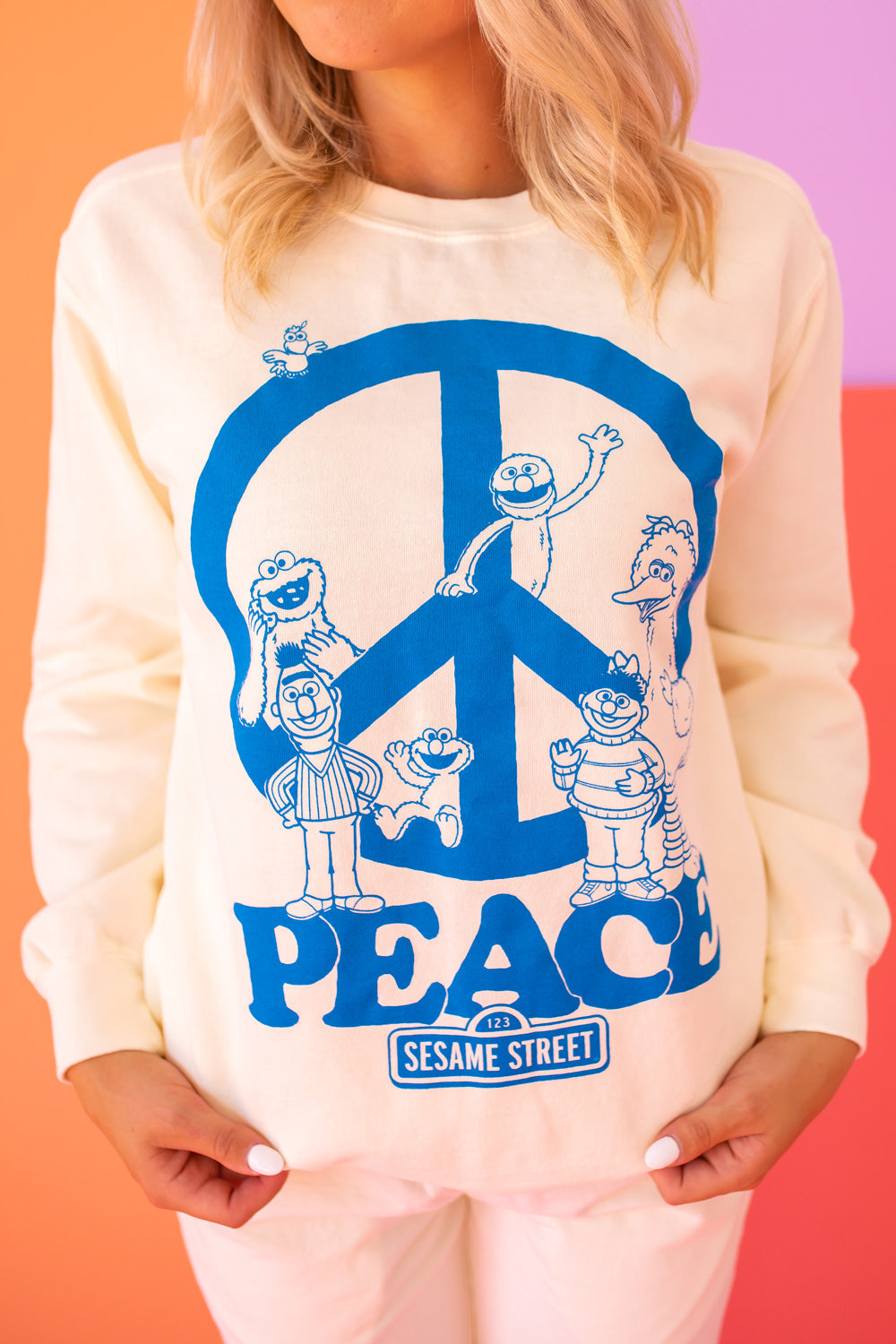 Ivory Sesame Street Peace Sweatshirt featuring bold graphics, made from 100% upcycled cotton, available in sizes S-XL.