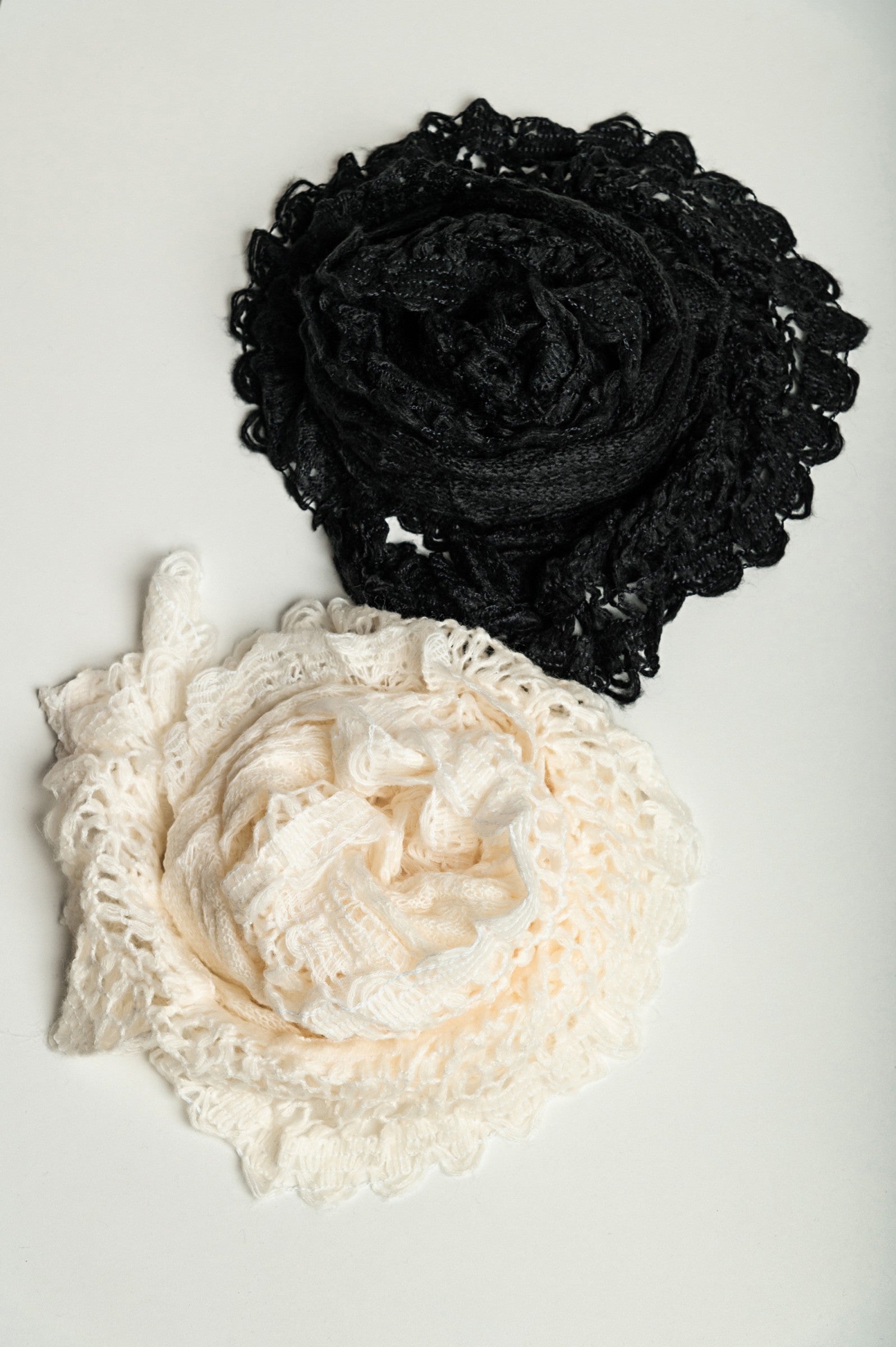 Set of 2 knitted scarves in white and black, showcasing their soft texture and stylish design.