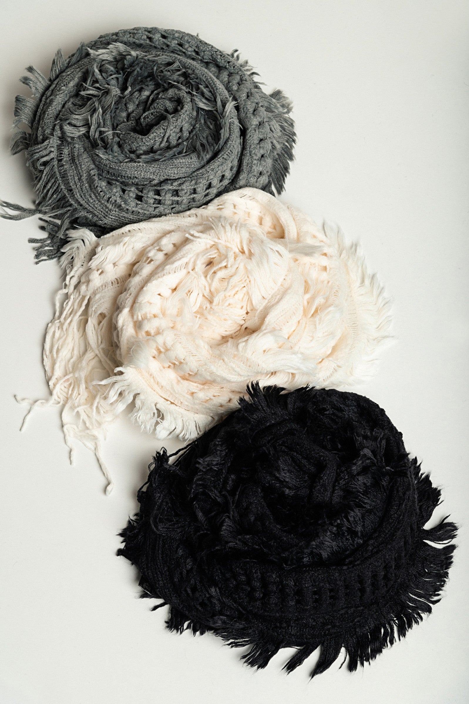 Set of 3 knitted scarves in white, black, and dark gray, showcasing their soft texture and stylish design.