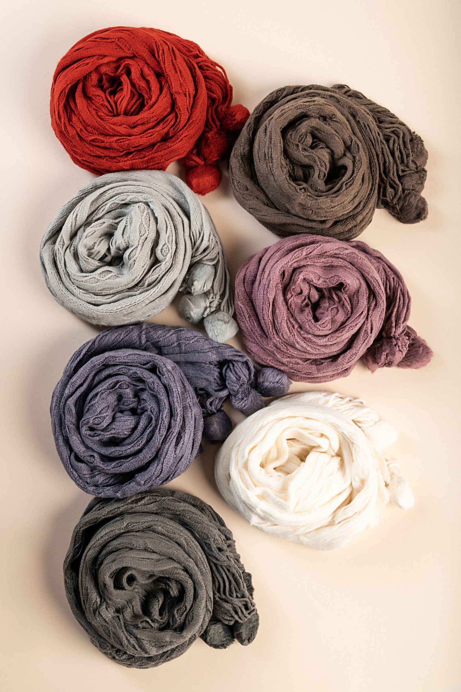 A vibrant set of 7 knitted scarves in various colors including white, dark gray, purple, pink, brown, and brick, showcasing their soft texture.