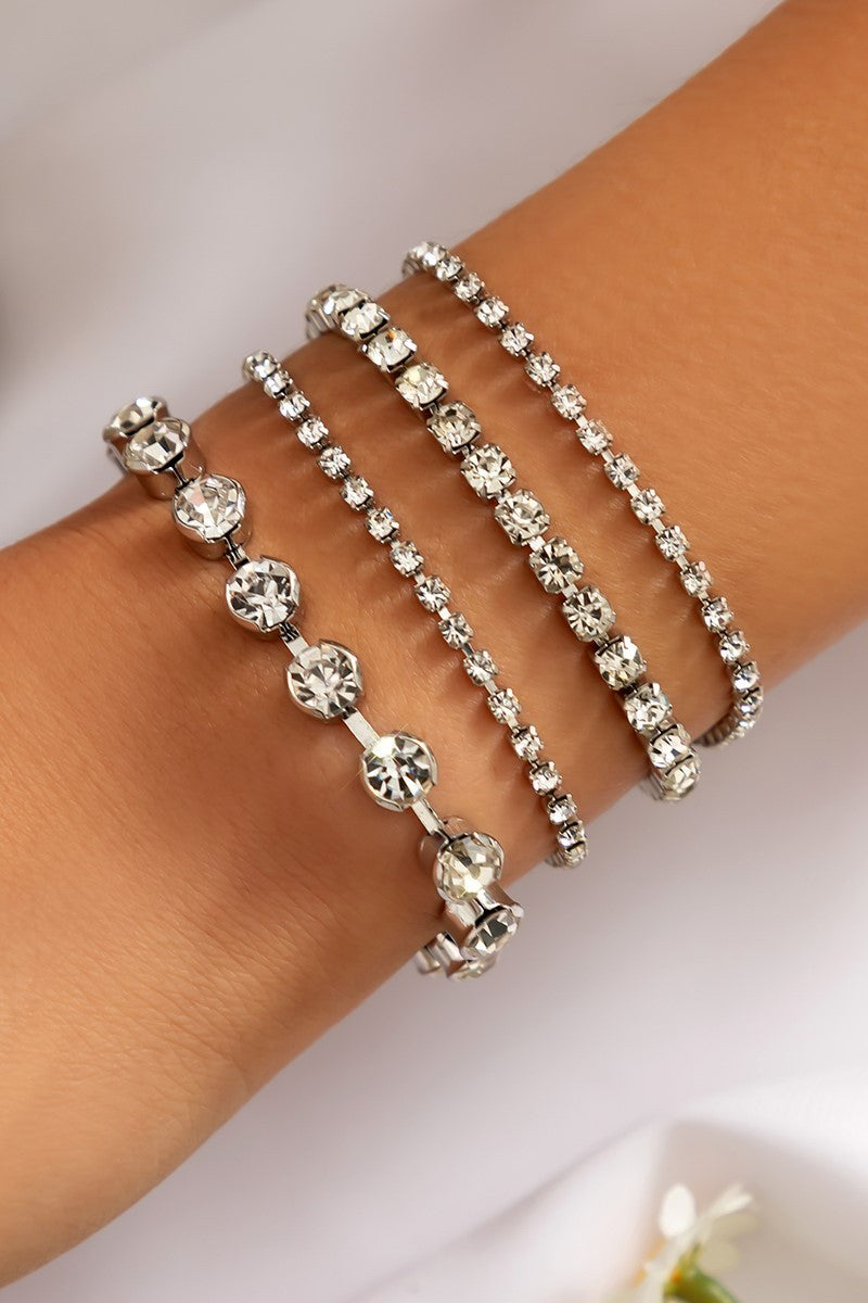 Set of four elegant white rhinestone bracelets with metal lobster clasp, showcasing decorative stones.