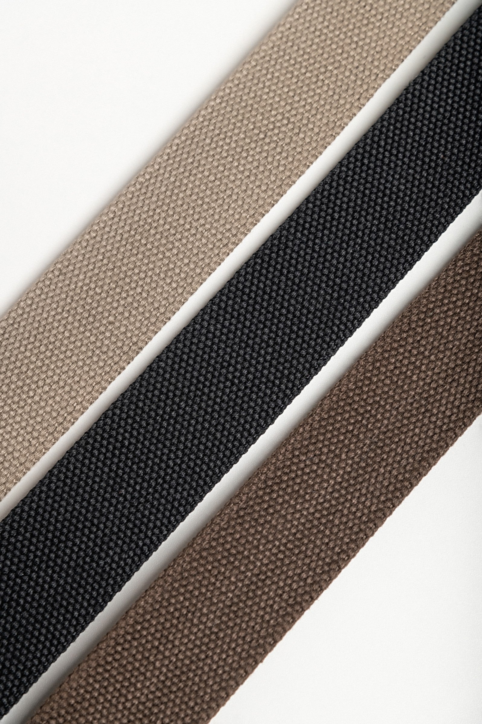 Set of three stylish belts in beige, black, and brown with metal buckles.