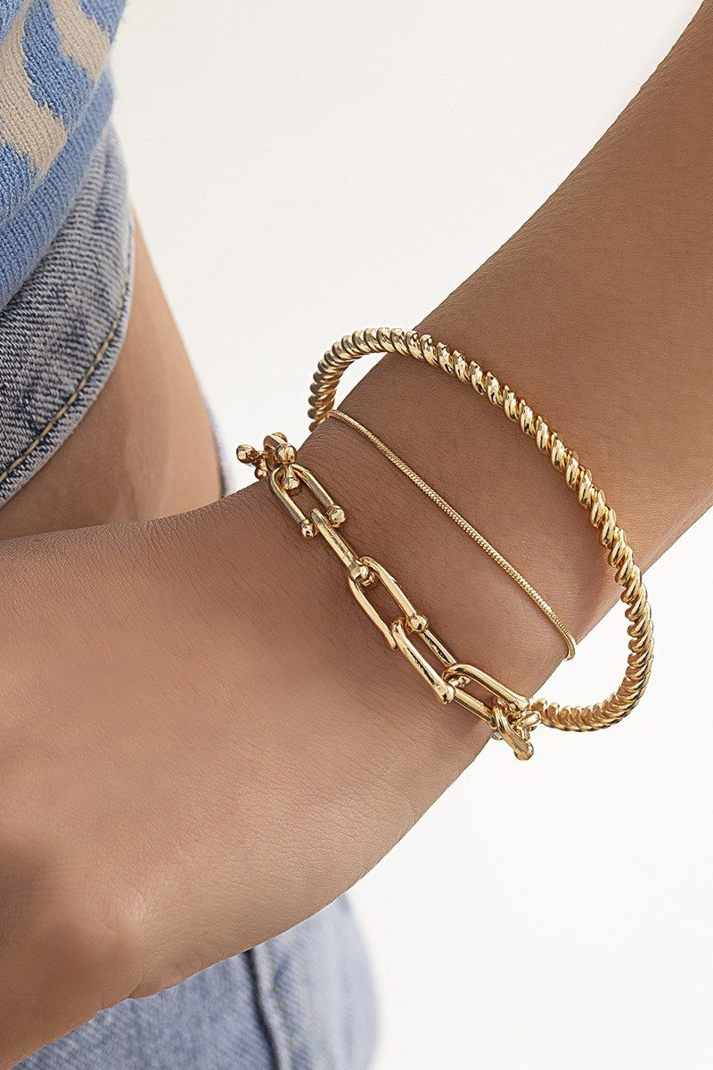 Set of three elegant gold bracelets in various shapes and sizes, showcasing unique motifs and a luxurious finish.