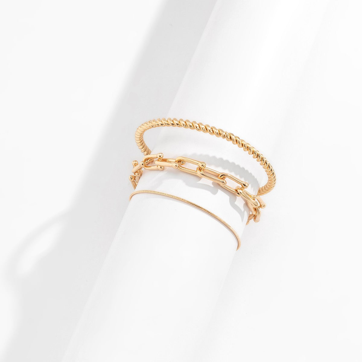 Set of three elegant gold bracelets in various shapes and sizes, showcasing unique motifs and a luxurious finish.