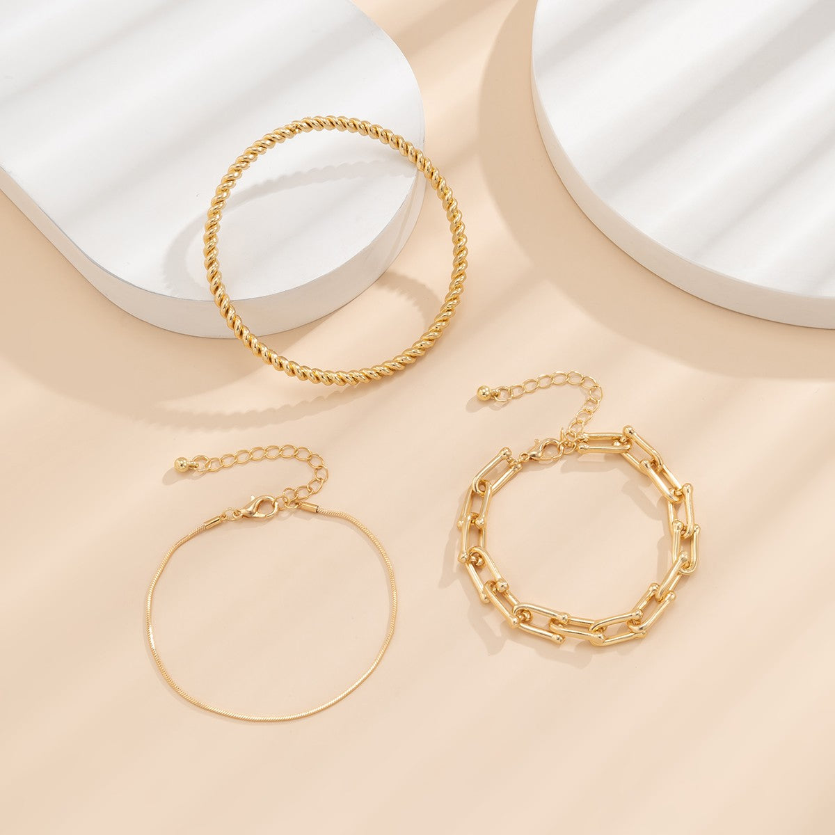 Set of three elegant gold bracelets in various shapes and sizes, showcasing unique motifs and a luxurious finish.