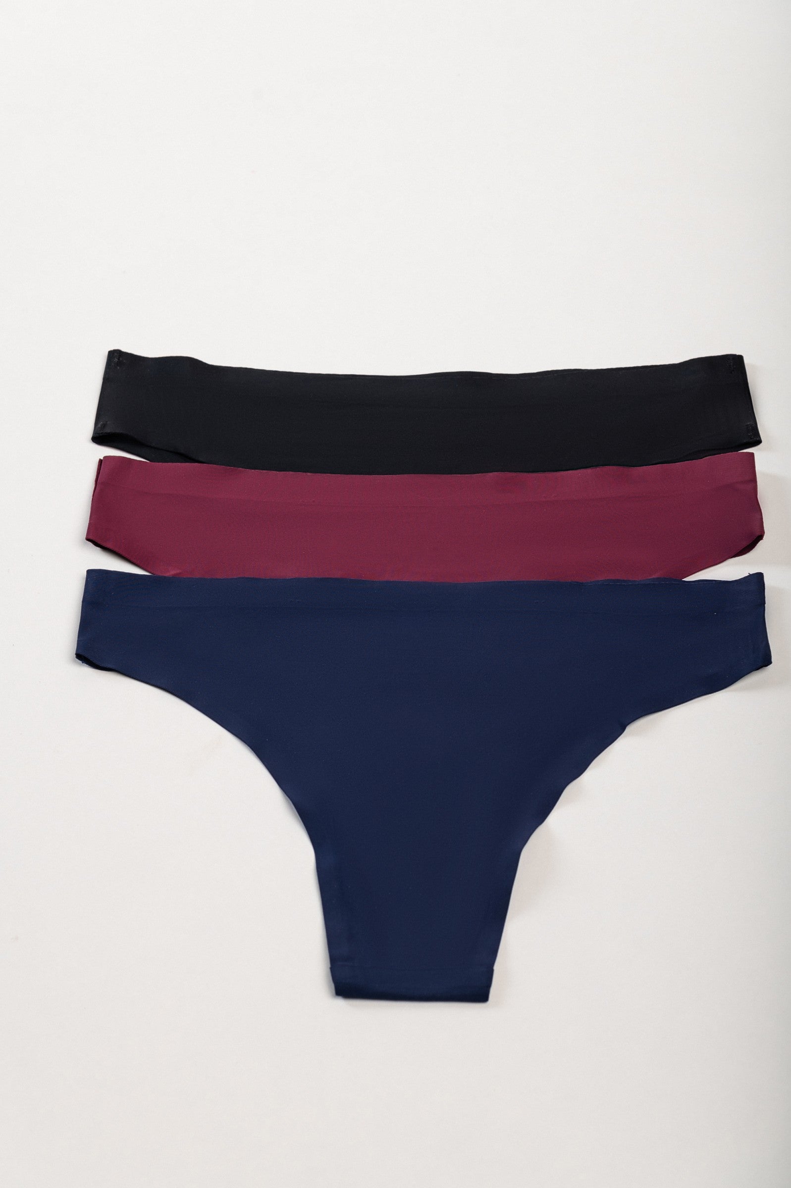 Set of three seamless panties in various colors including black, burgundy, and dark blue, showcasing their smooth and comfortable design.