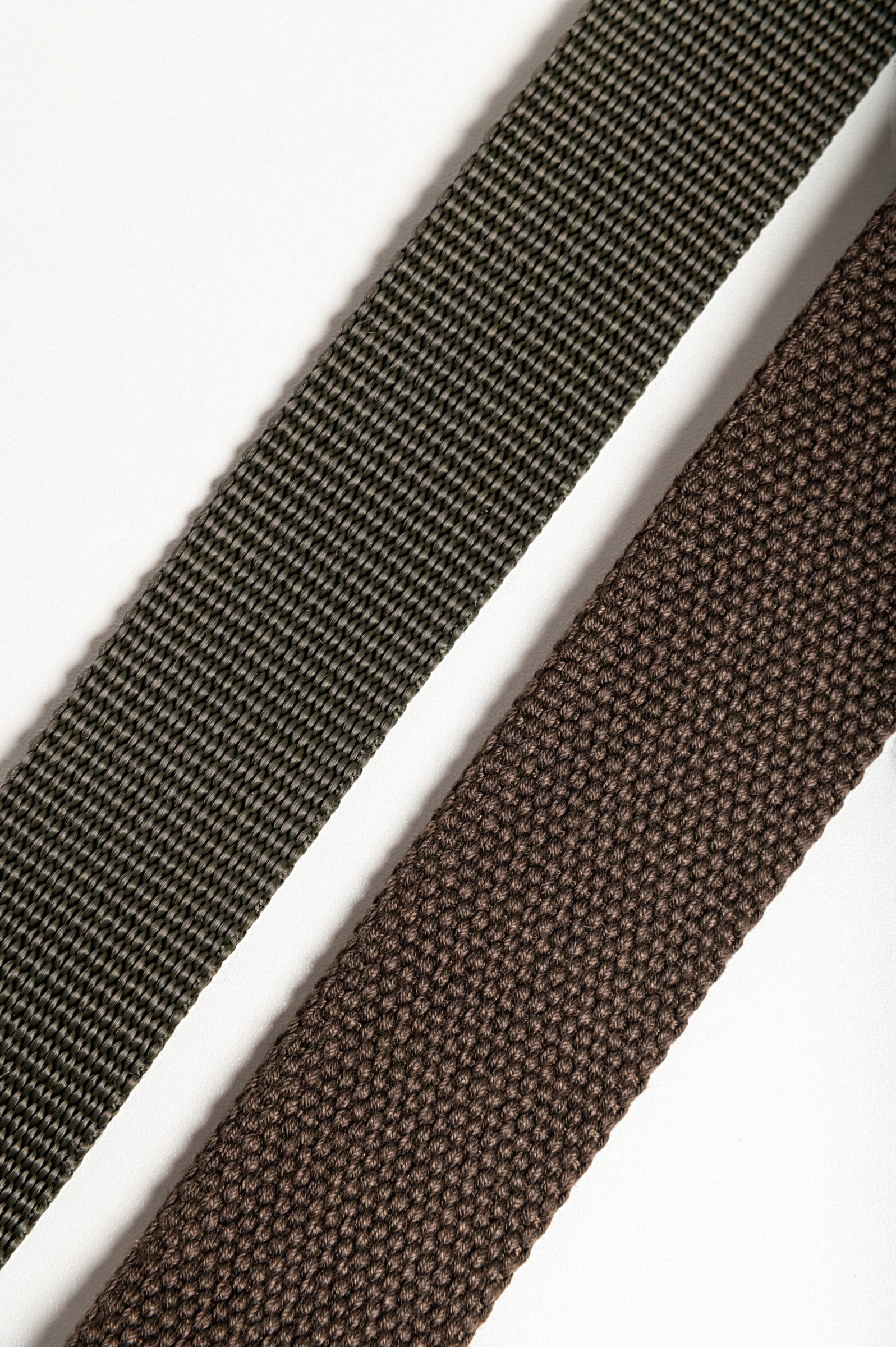 Set of two multicolored belts in brown and green with metal buckles, showcasing their adjustable lengths and durable material.