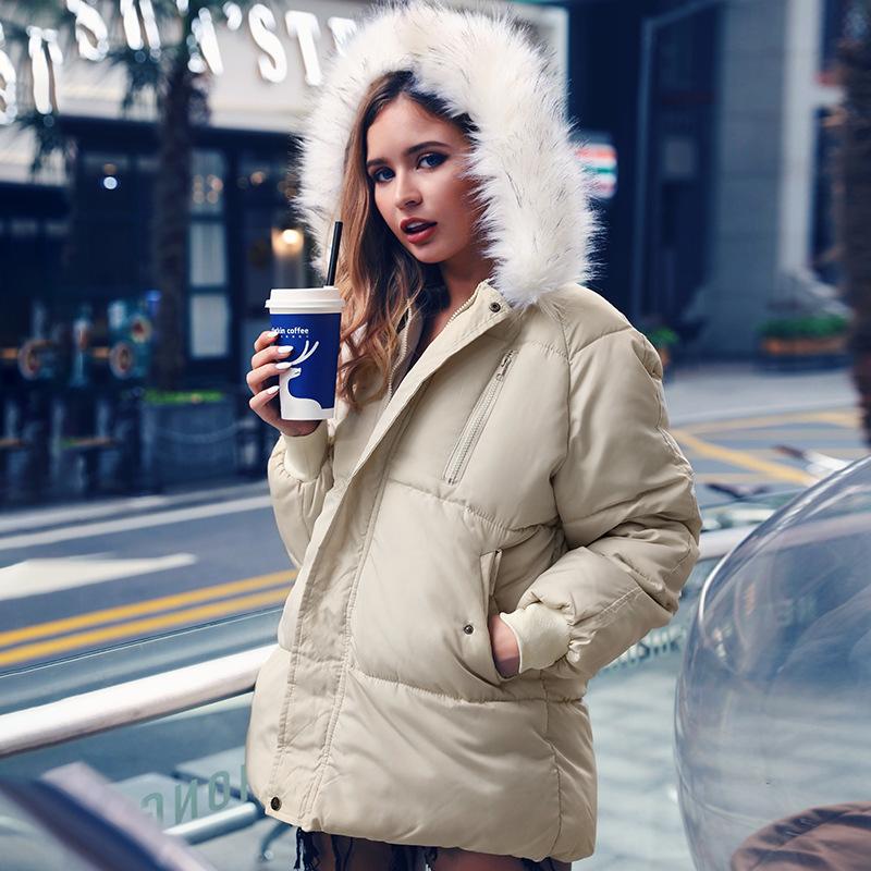 A stylish female model wearing a sexy winter warm hooded down jacket with a fur collar, showcasing its slim fit and zipper closure.