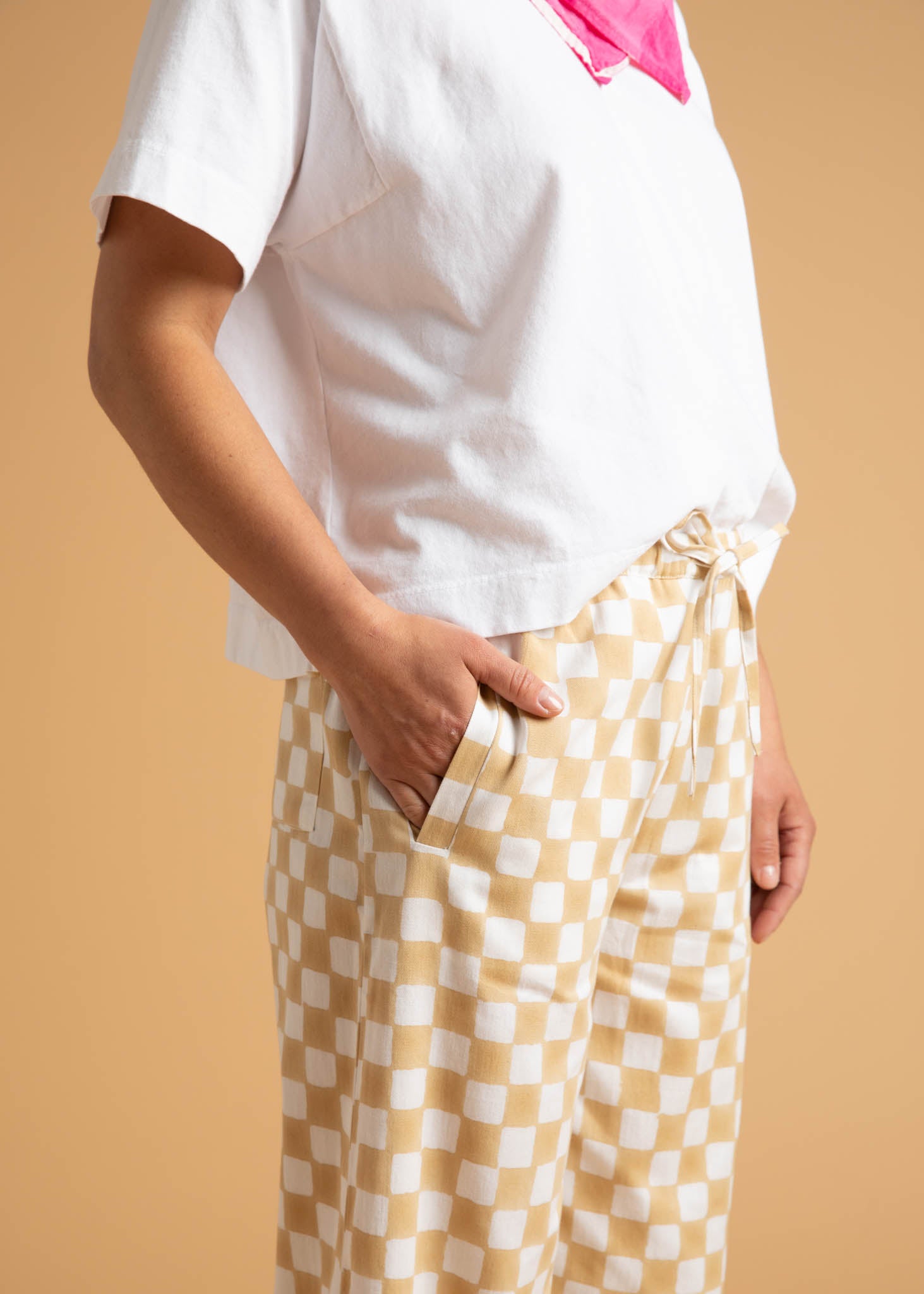 A pair of Shore Pants in Checkerboard Natural pattern, showcasing a modern cropped length and relaxed fit, made from organic cotton.