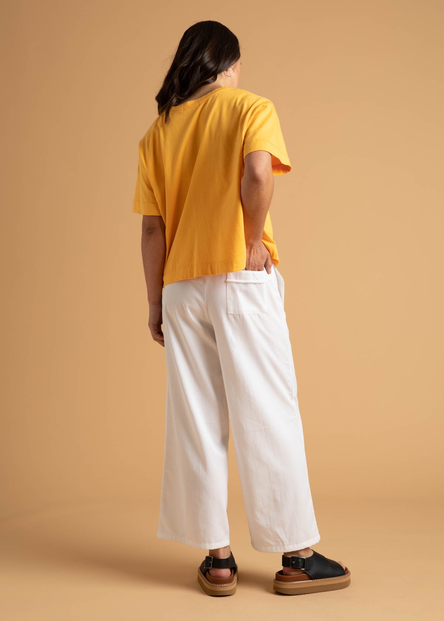 A pair of Shore Pants in Natural color, featuring a modern cropped length, relaxed fit, and elastic waist, displayed on a neutral background.